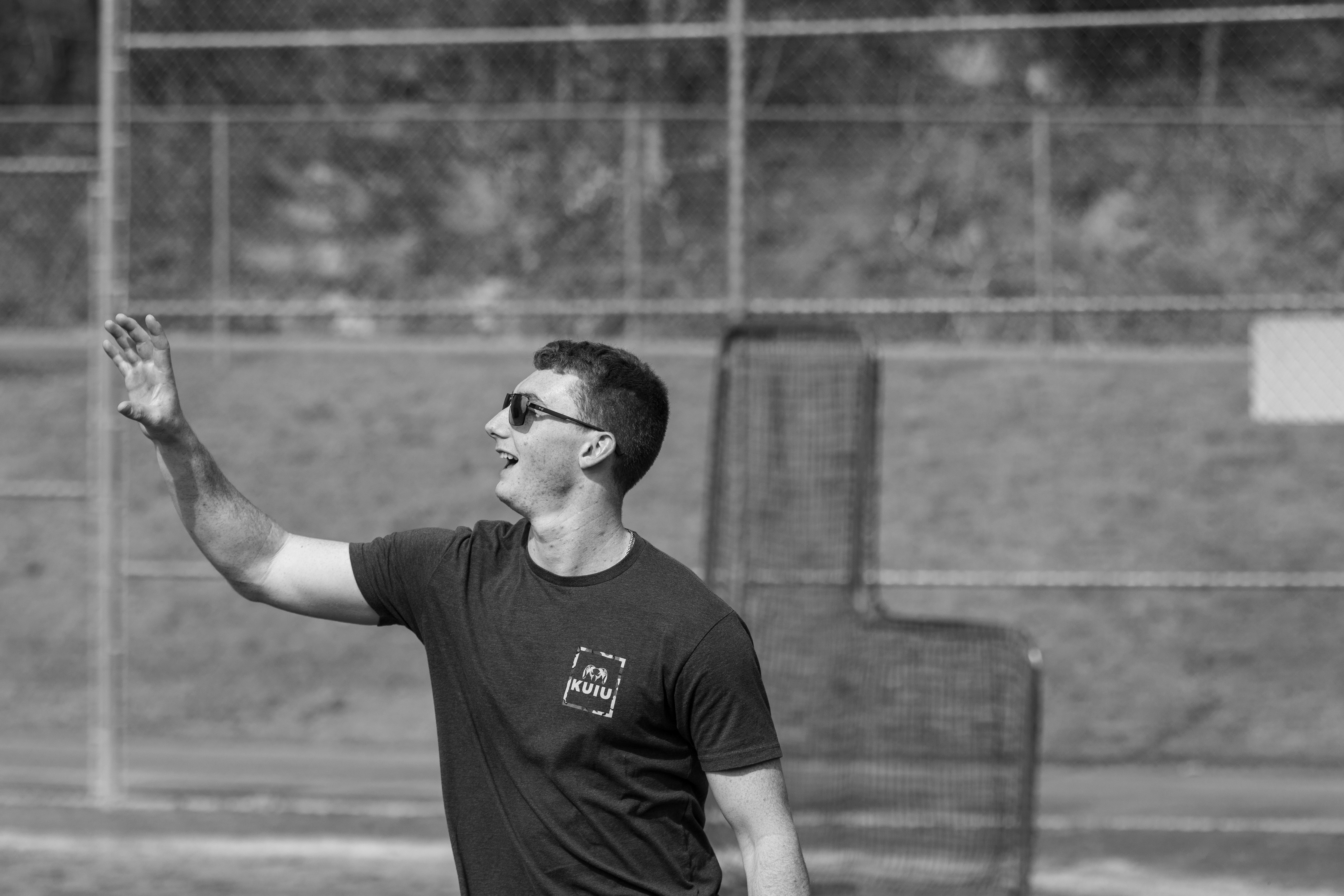 Man in sunglasses waves on a sports field