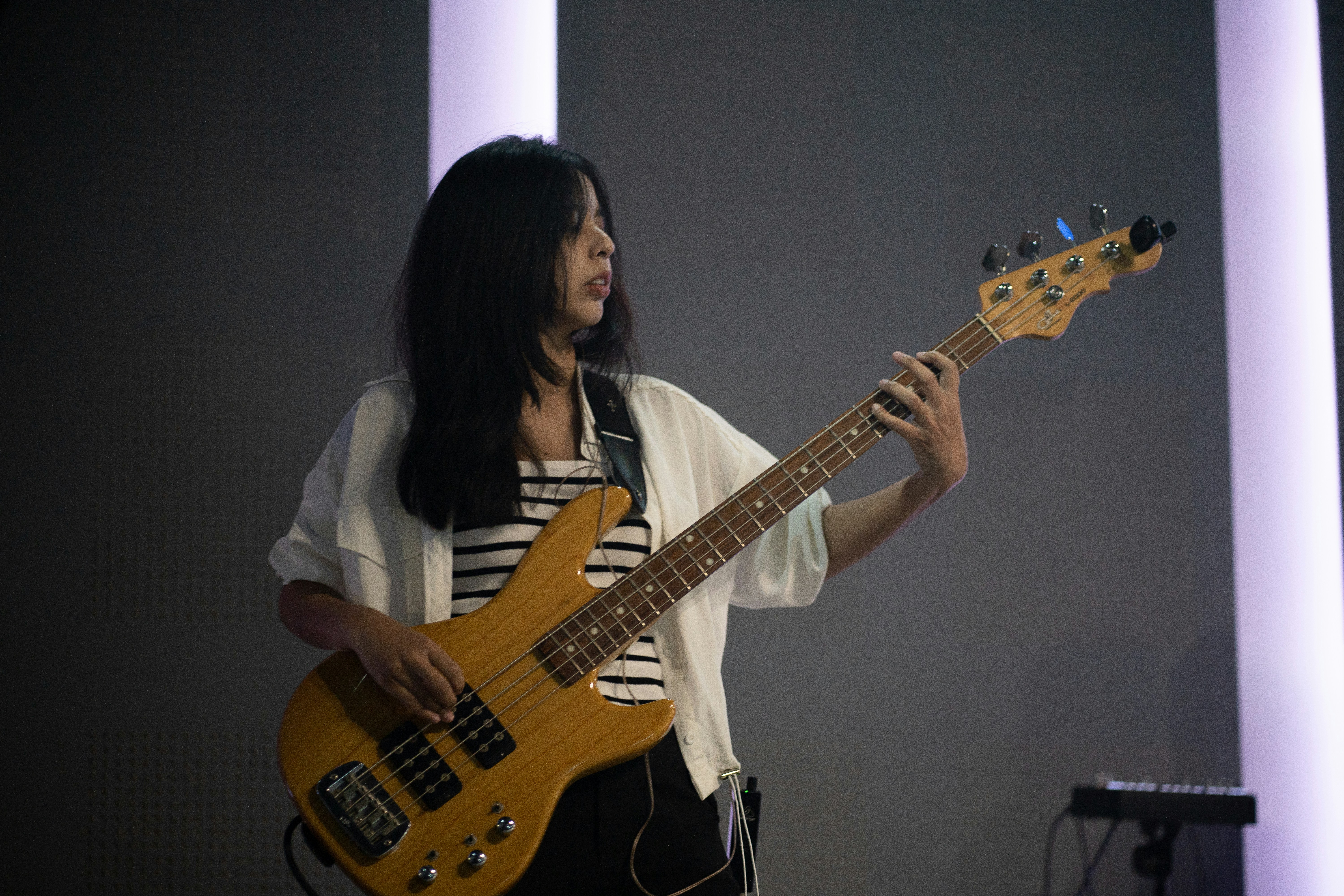A woman playing a bass guitar on stage.