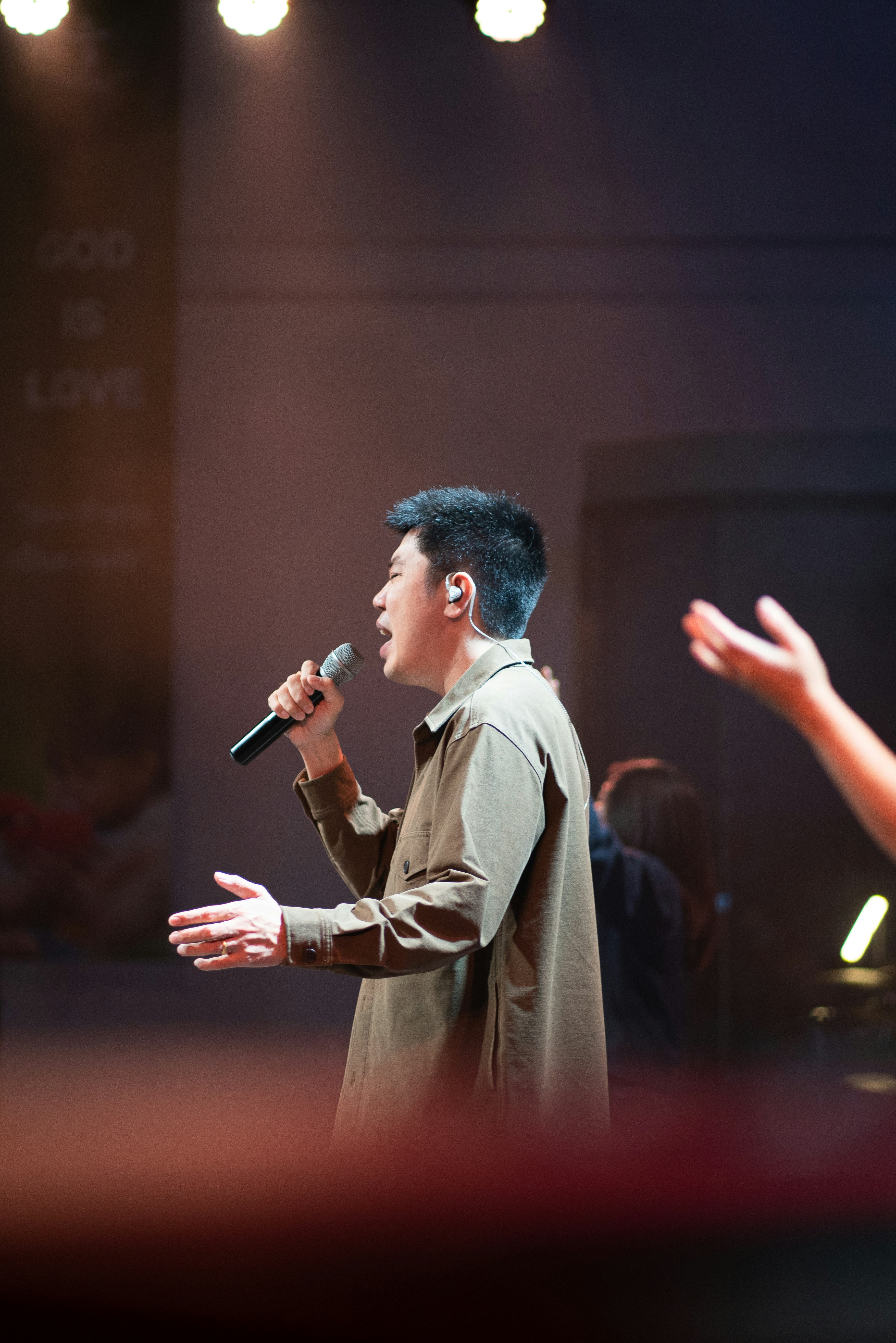 Man singing into microphone on stage with lights