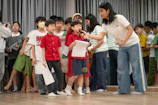 A woman with a microphone interacts with children.