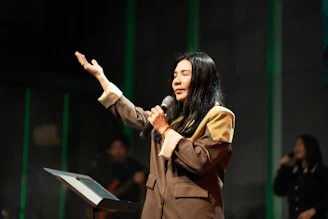 A woman sings into a microphone on stage.