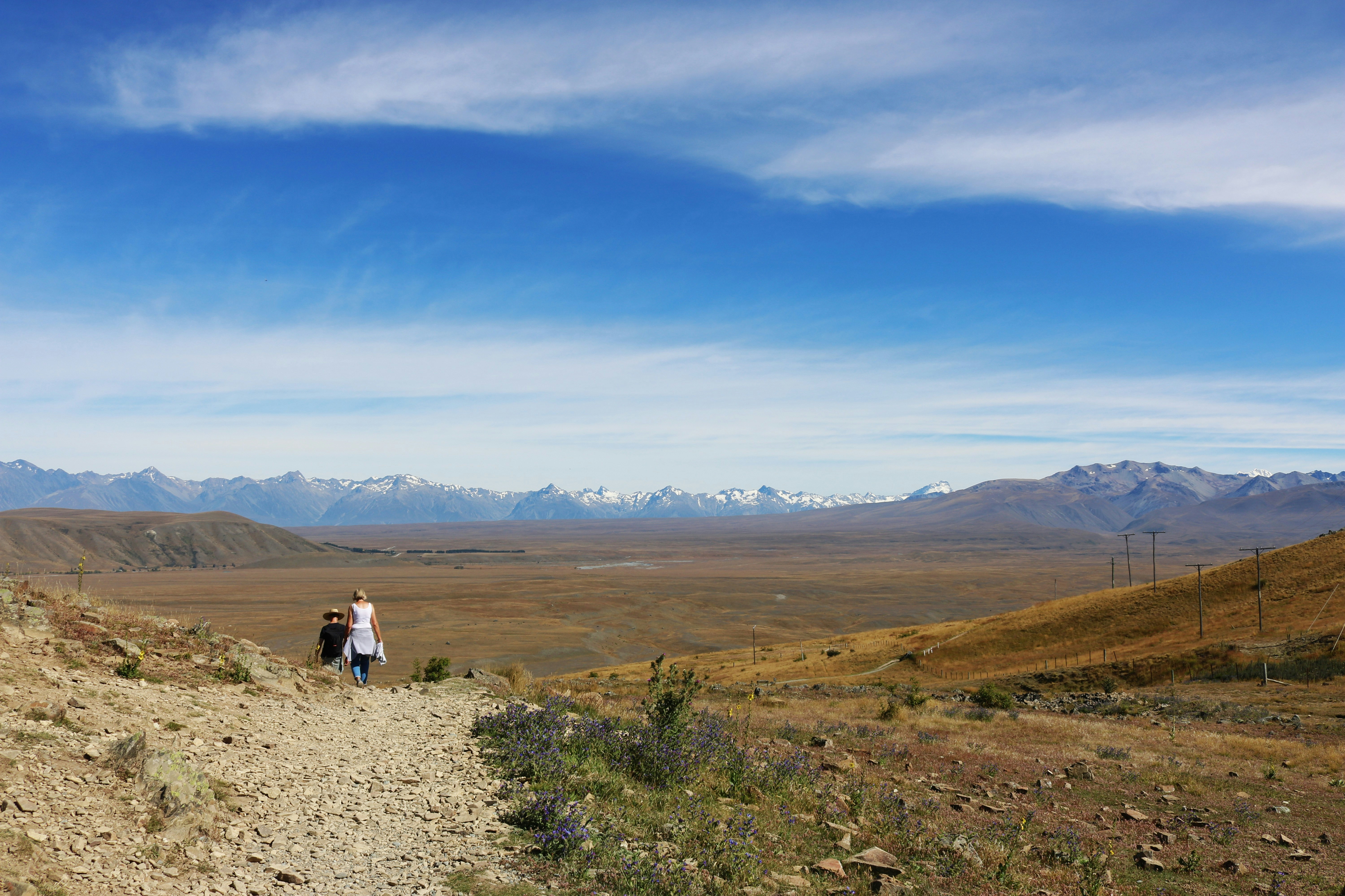 Two people walking on a dirt path overlooking a valley 풍경 사진