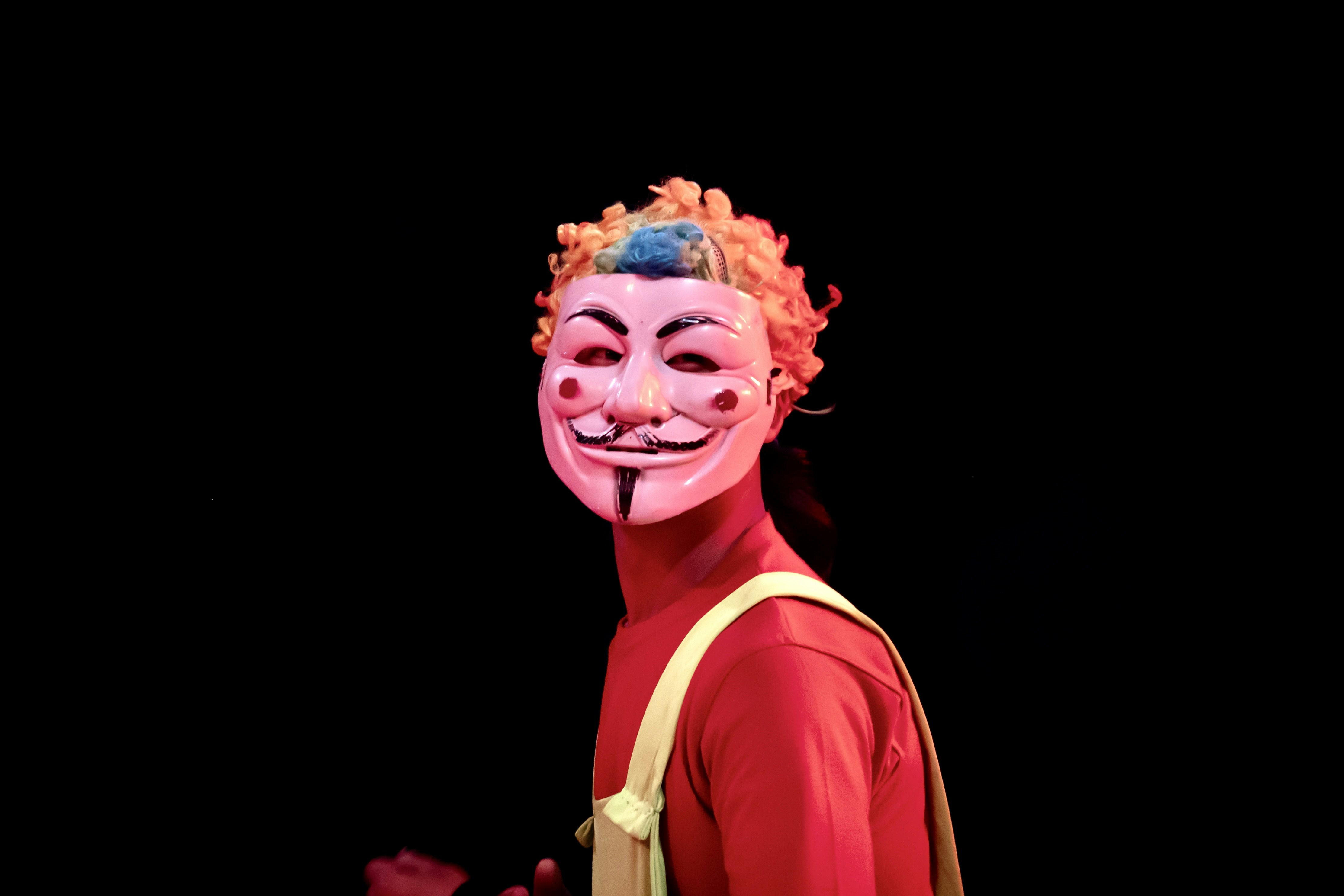 Personne portant le masque de Guy Fawkes avec des cheveux orange