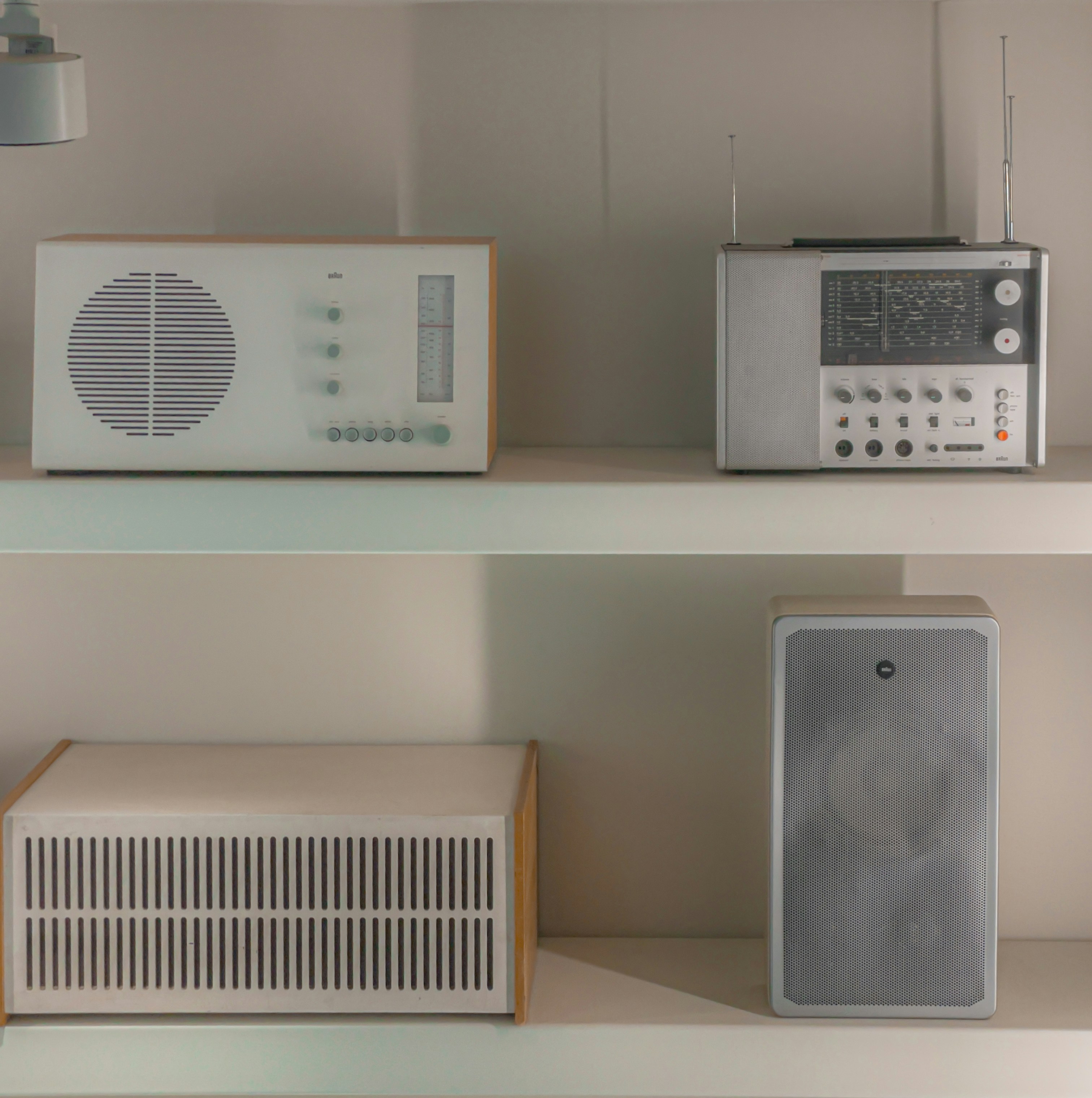 Four vintage radios and speakers displayed on shelves.