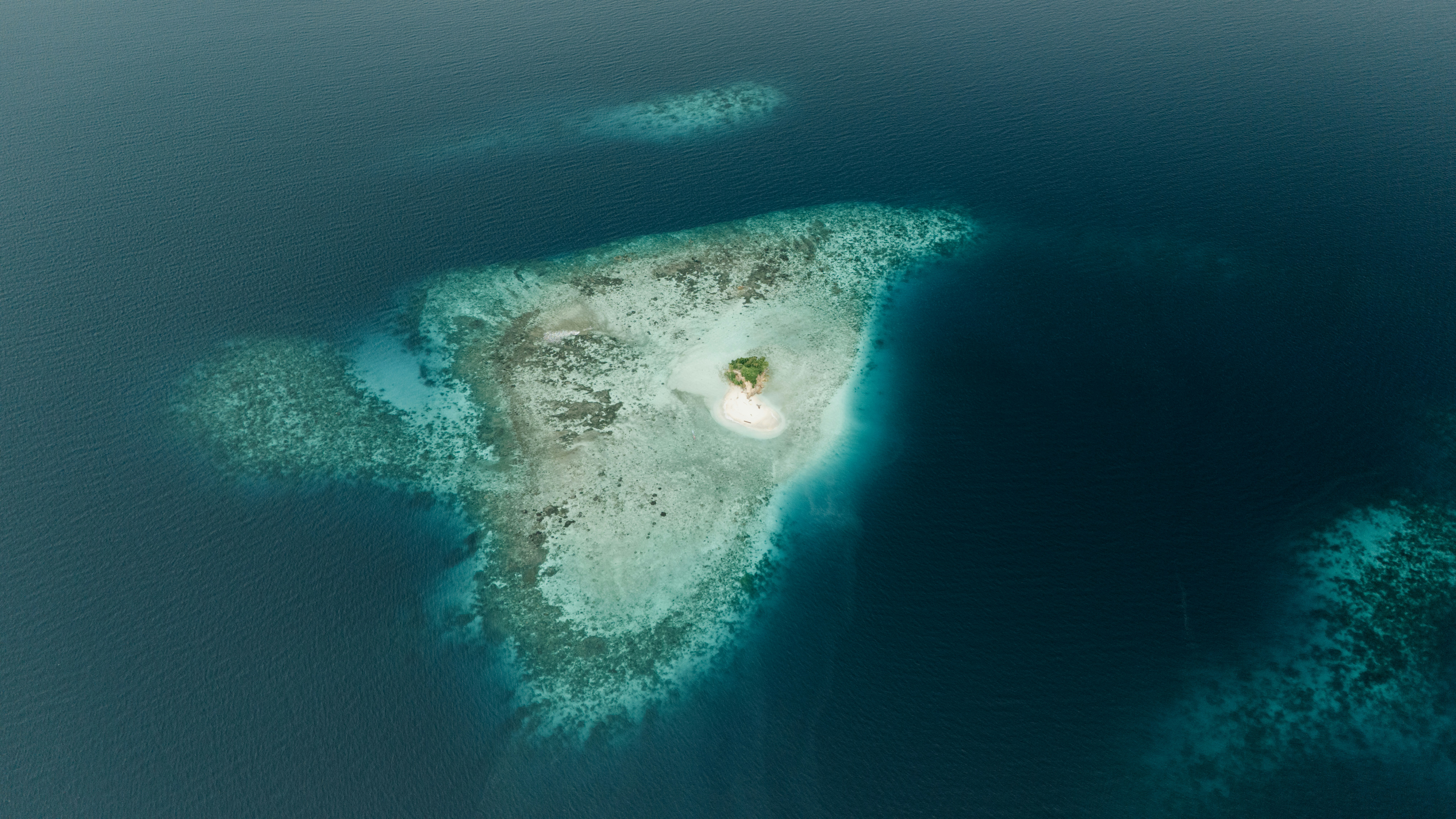 Aerial view of a small island surrounded by coral reefs.