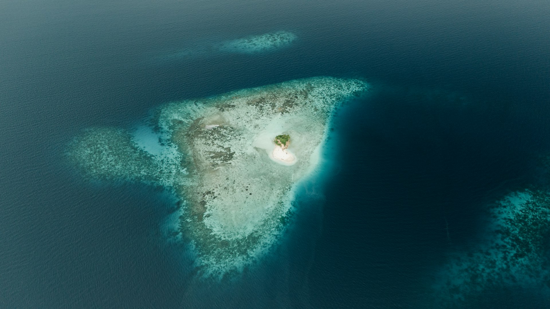 Vue aérienne spectaculaire d une petite île entourée de récifs coralliens et d eaux turquoises