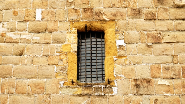 A small barred window set in a stone wall