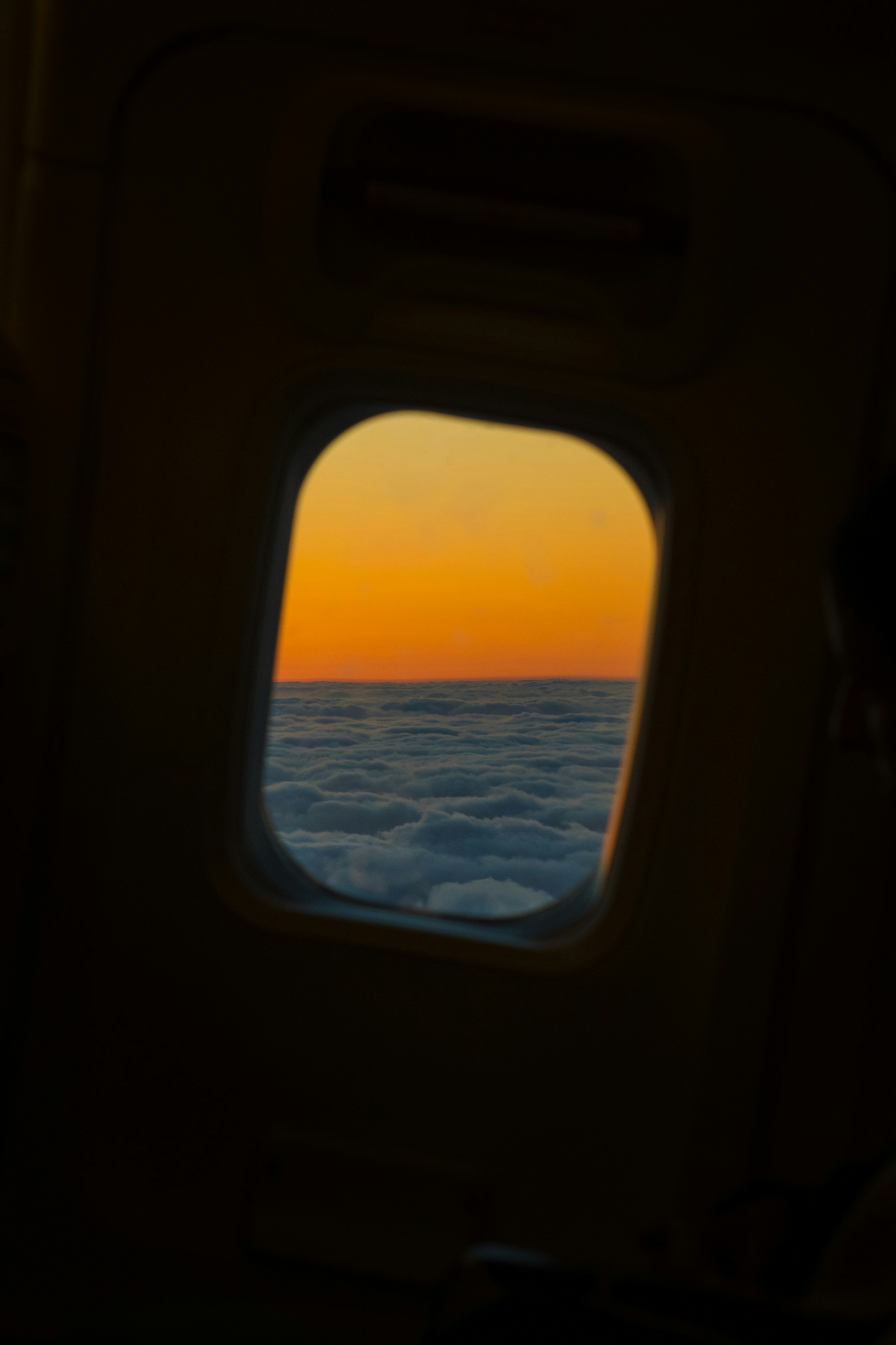 Sunset viewed from an airplane window above clouds