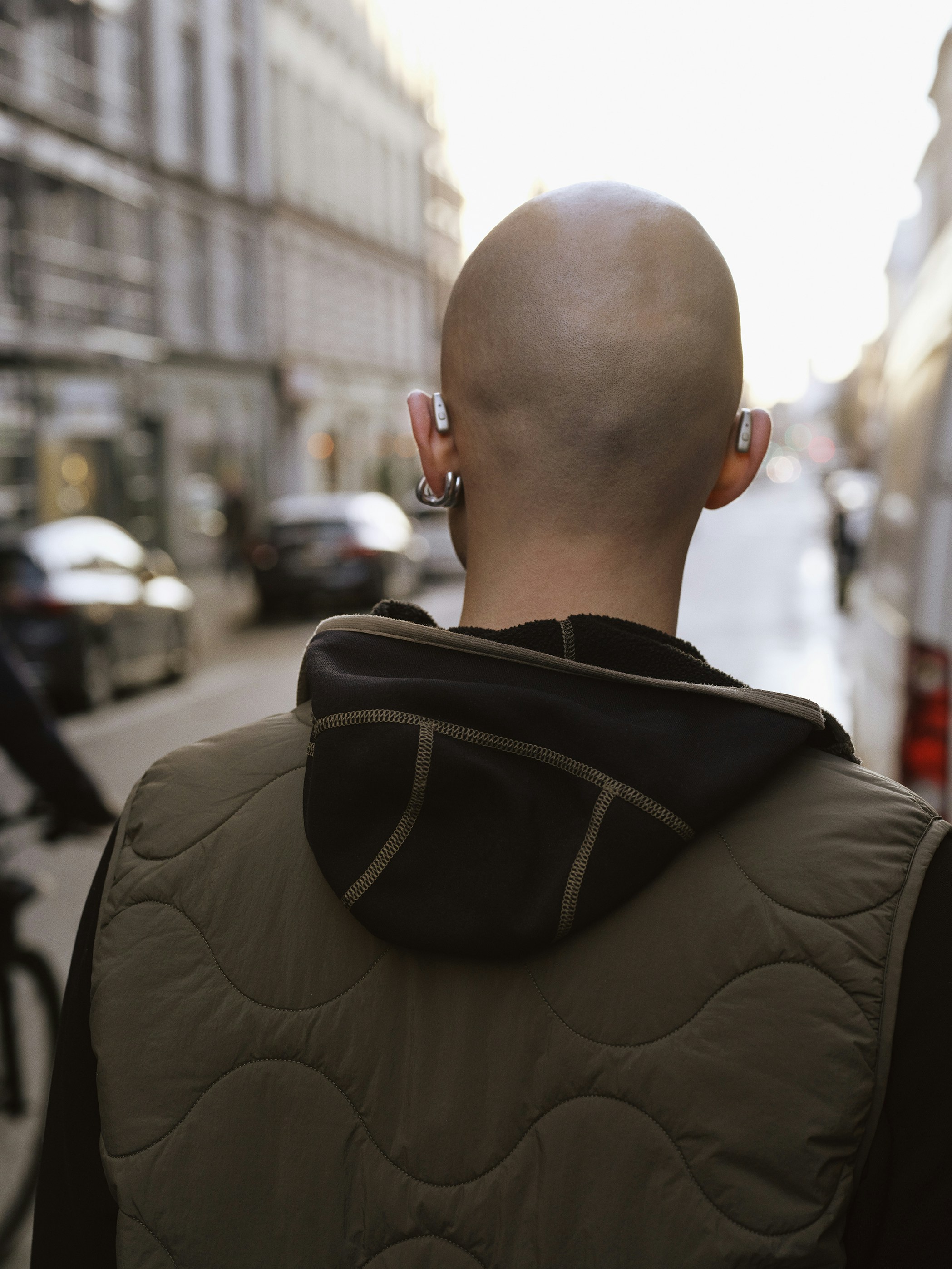 Bald person in a vest on a city street