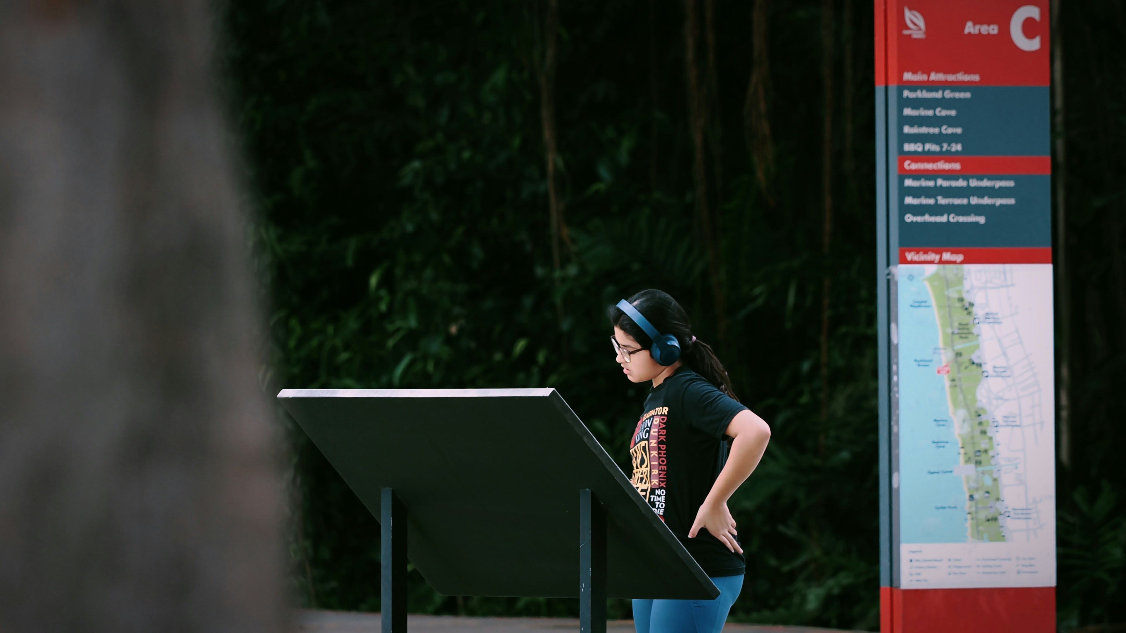 A woman wearing headphones looks at a map.
