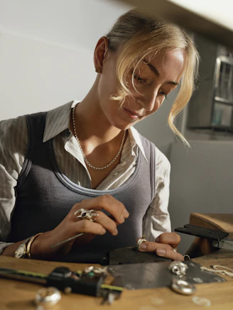 A woman working on jewelry at a workbench.