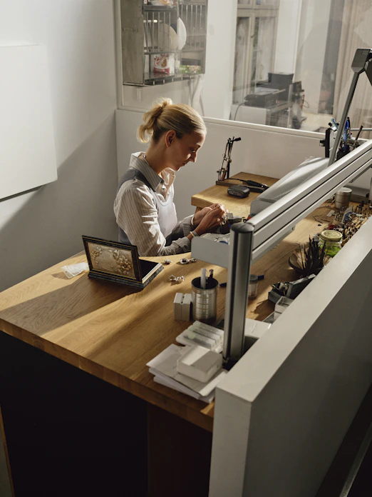 Woman working at a jewelry making bench.