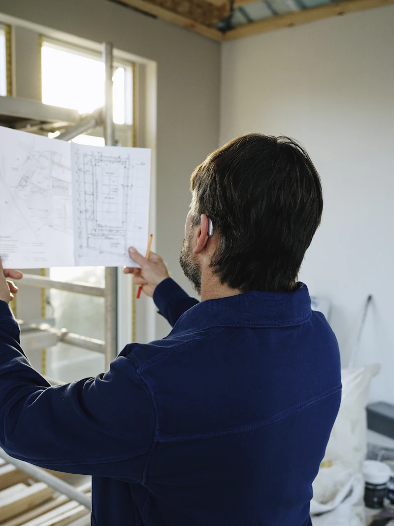 Builder reviewing floor plans at an active framing site