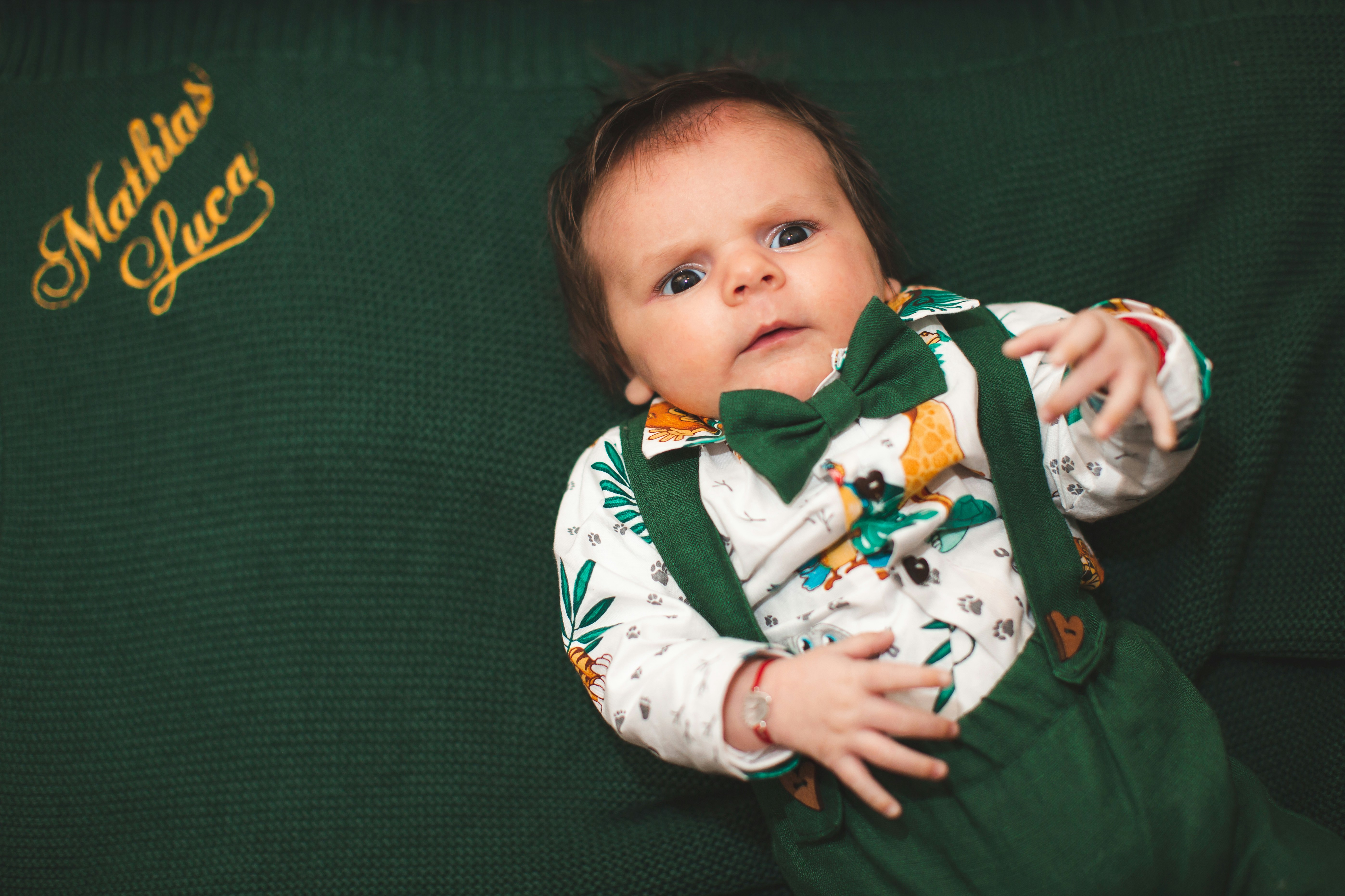 Un bebé con un traje verde y pajarita.