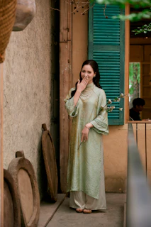 Woman in traditional vietnamese ao dai laughs shyly.