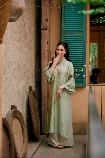 Woman in traditional vietnamese ao dai laughs shyly.