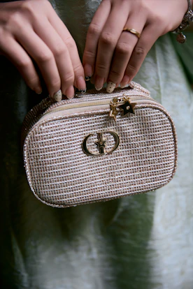 Woman holding a small, sparkly handbag with a gold logo.