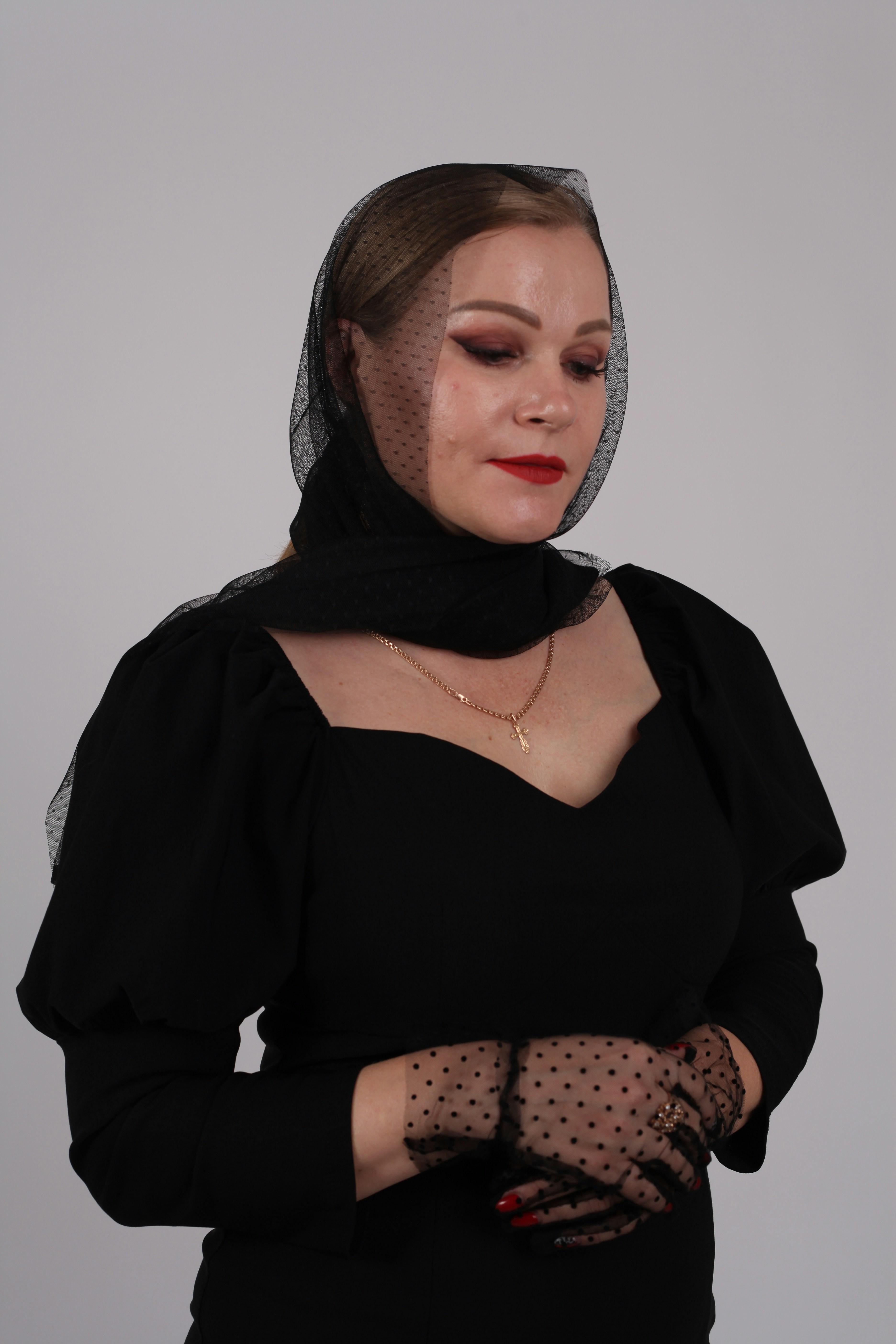 Woman in black dress with polka dot veil and gloves