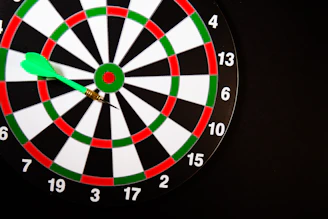 A green dart stuck in a dartboard on black background