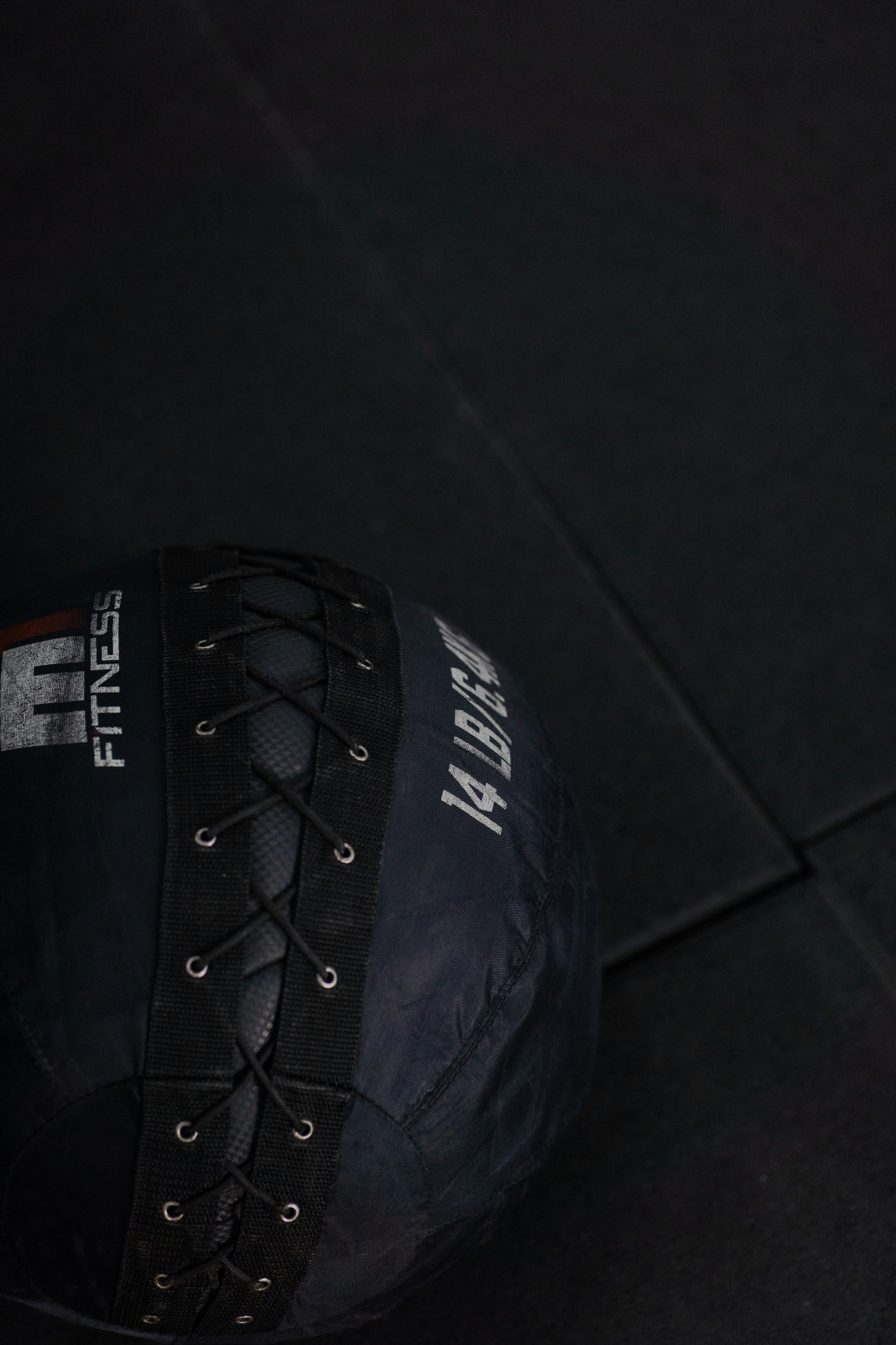 A blue 14 lb medicine ball on a black floor.