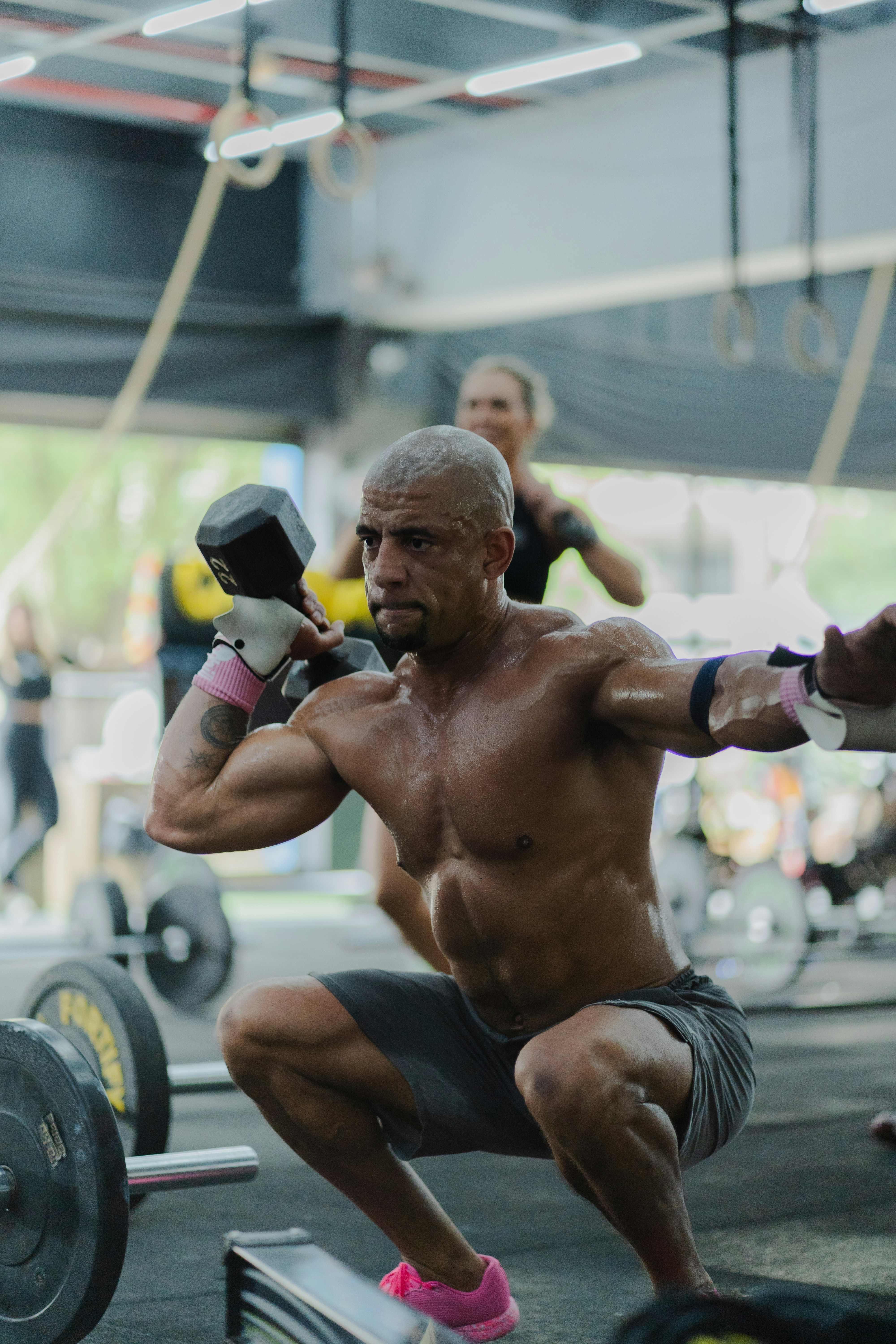 Man performing a dumbbell squat exercise in gym