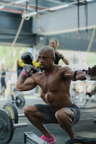 Man performing a dumbbell squat exercise in gym