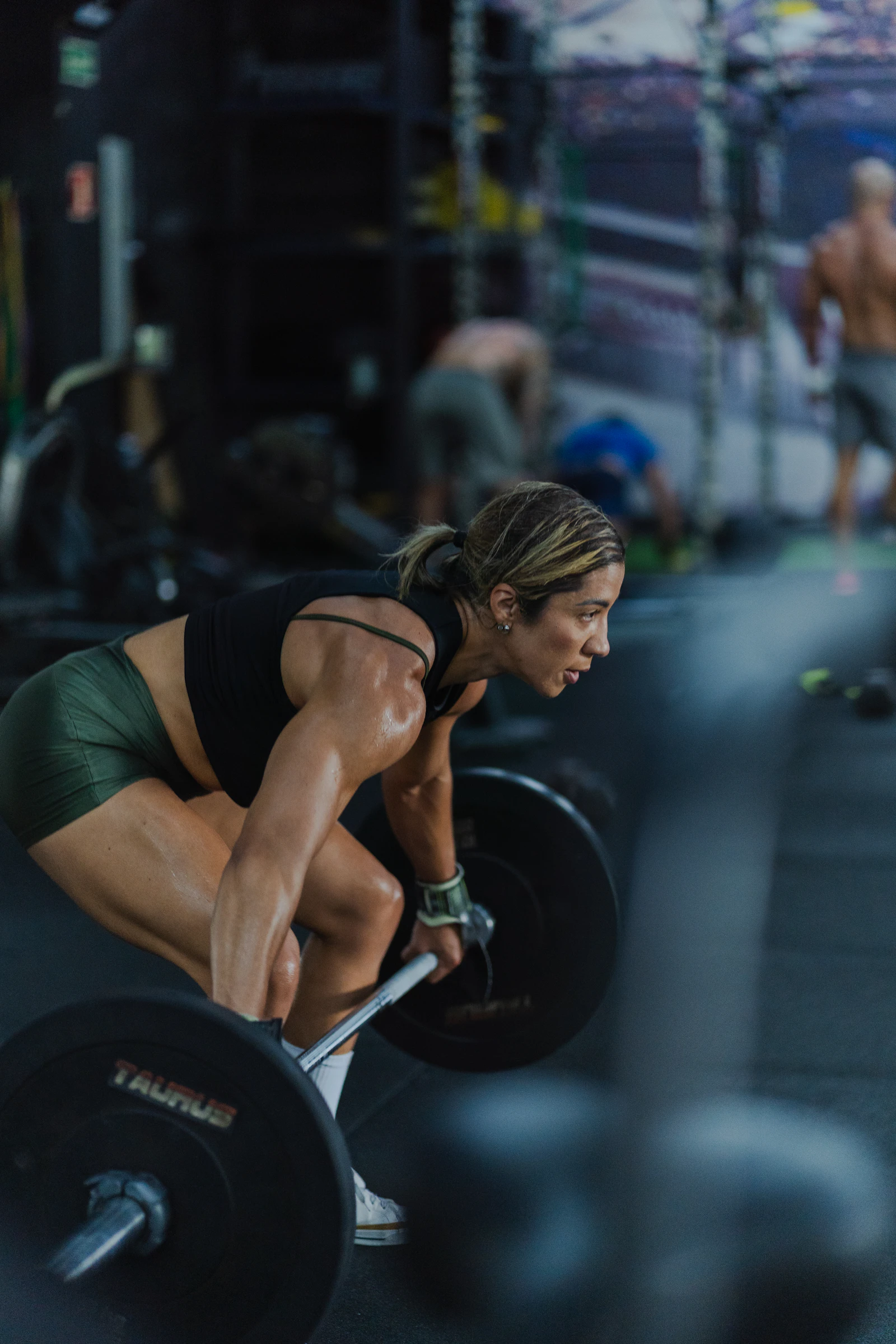 Athlete setting up a deadlift on a dark training floor