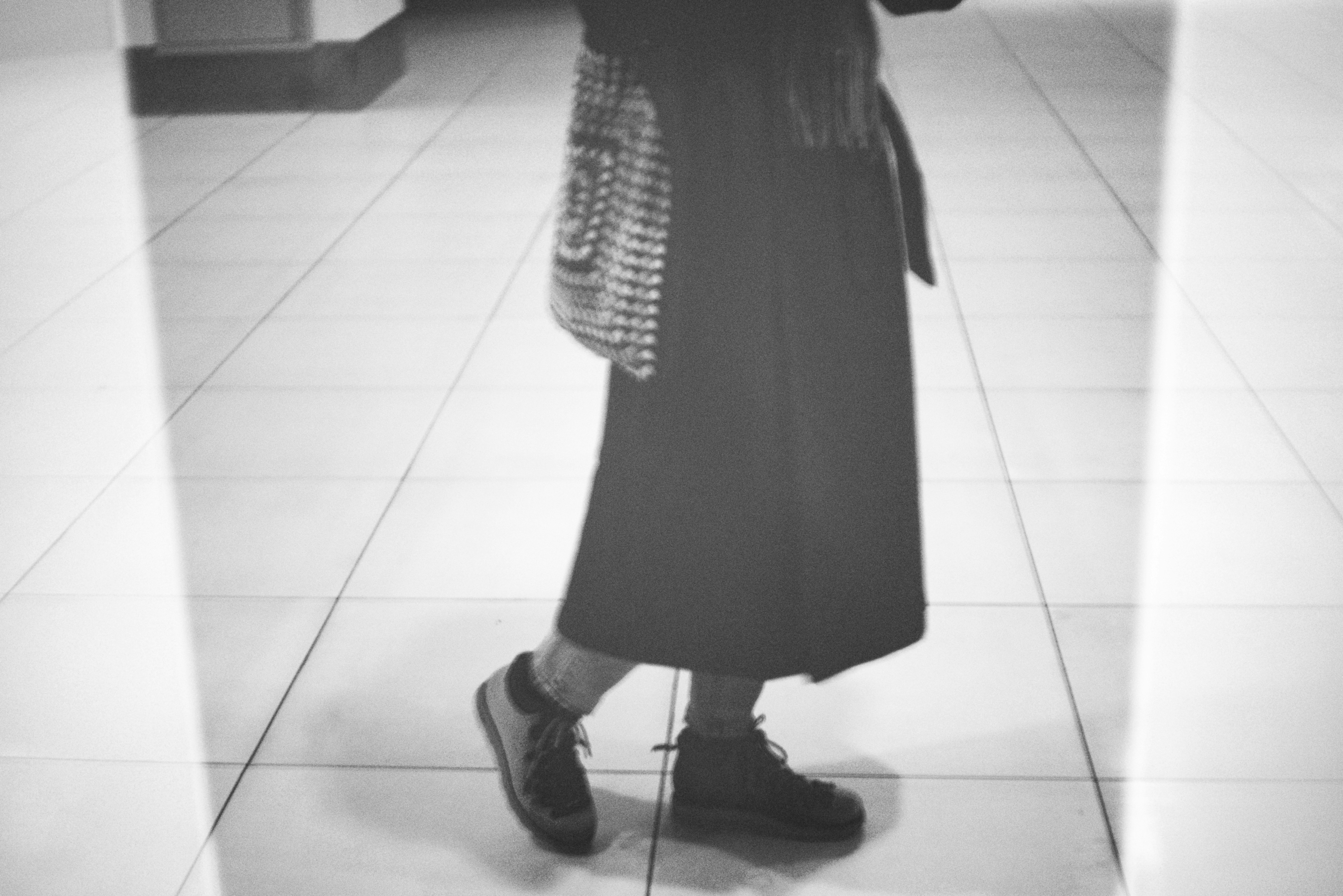 Person walking on tiled floor with bag
