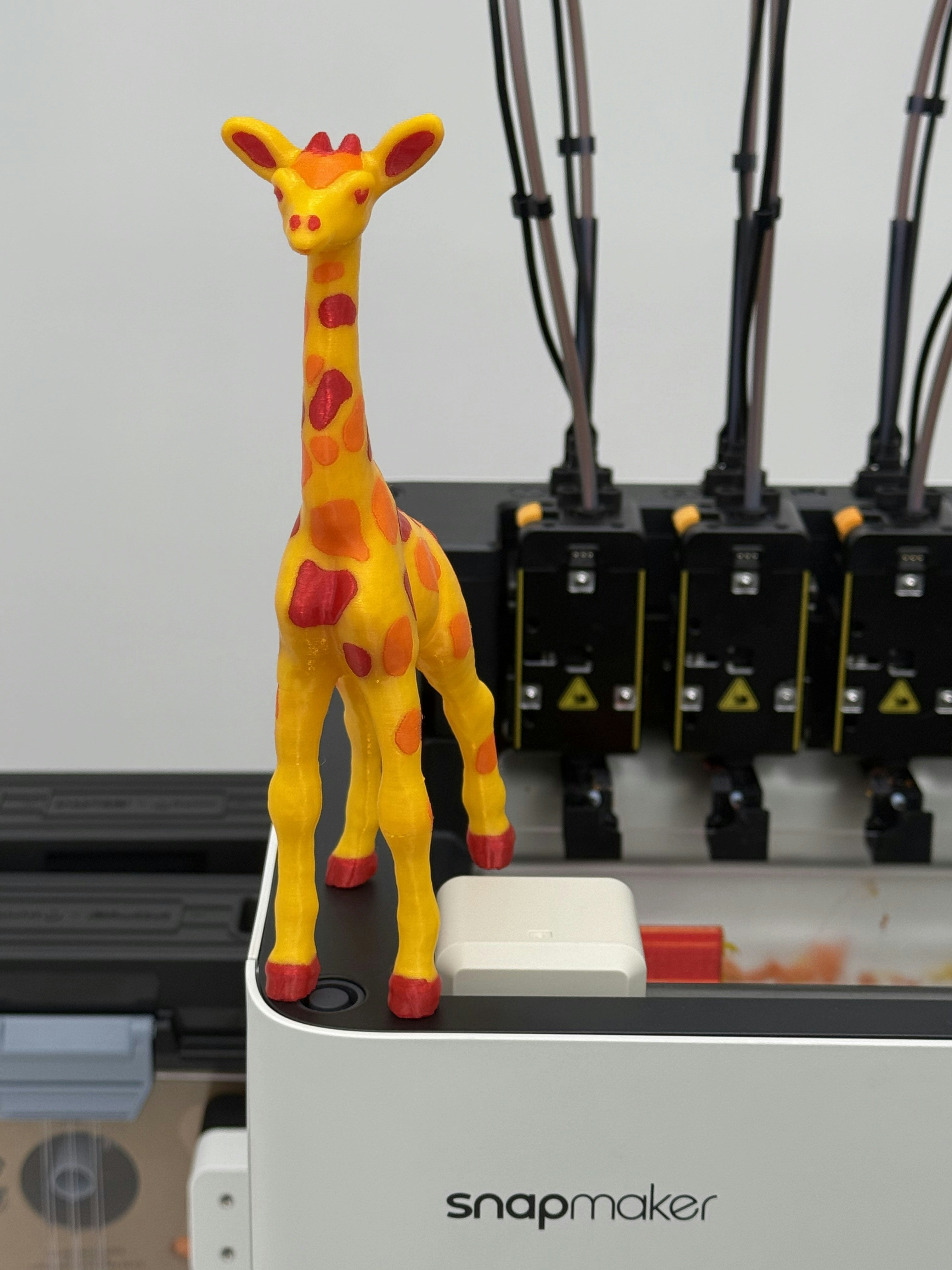 A yellow and orange giraffe toy on a white machine.
