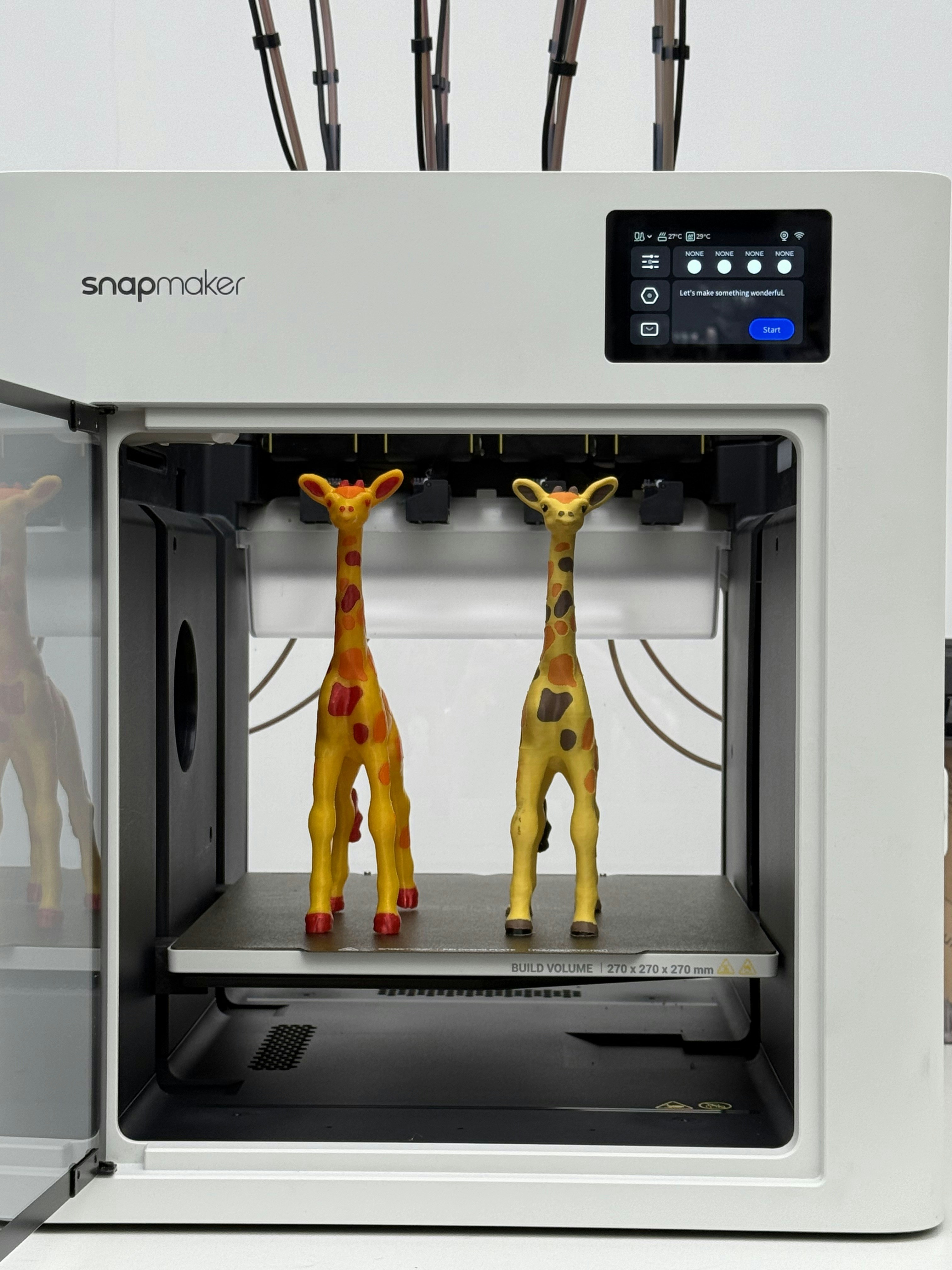 Two giraffe figures inside a 3D printer