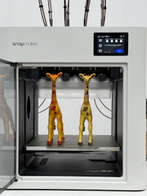 Two giraffe figures inside a 3D printer