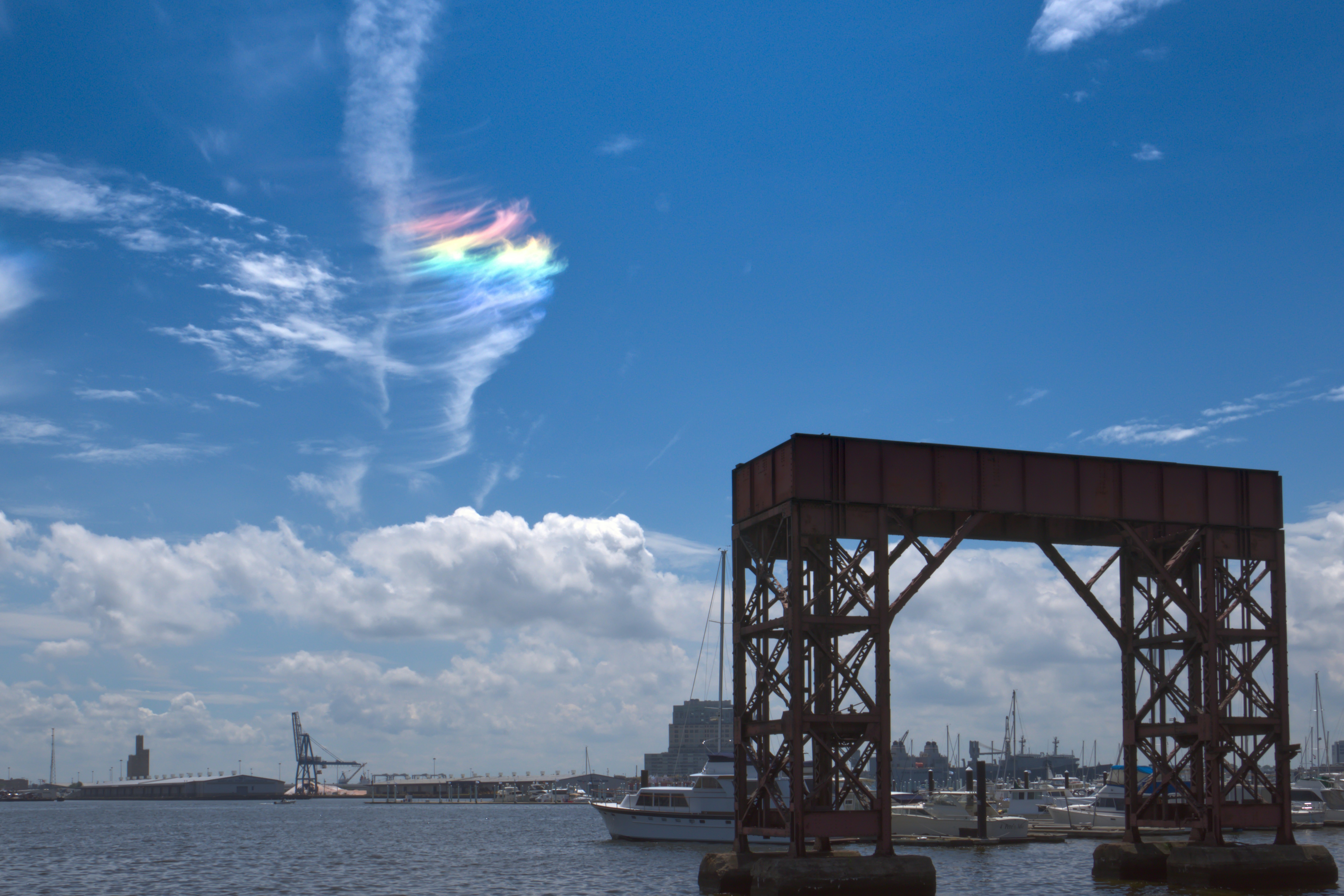 Arco industrial sobre el agua con barcos y nubes