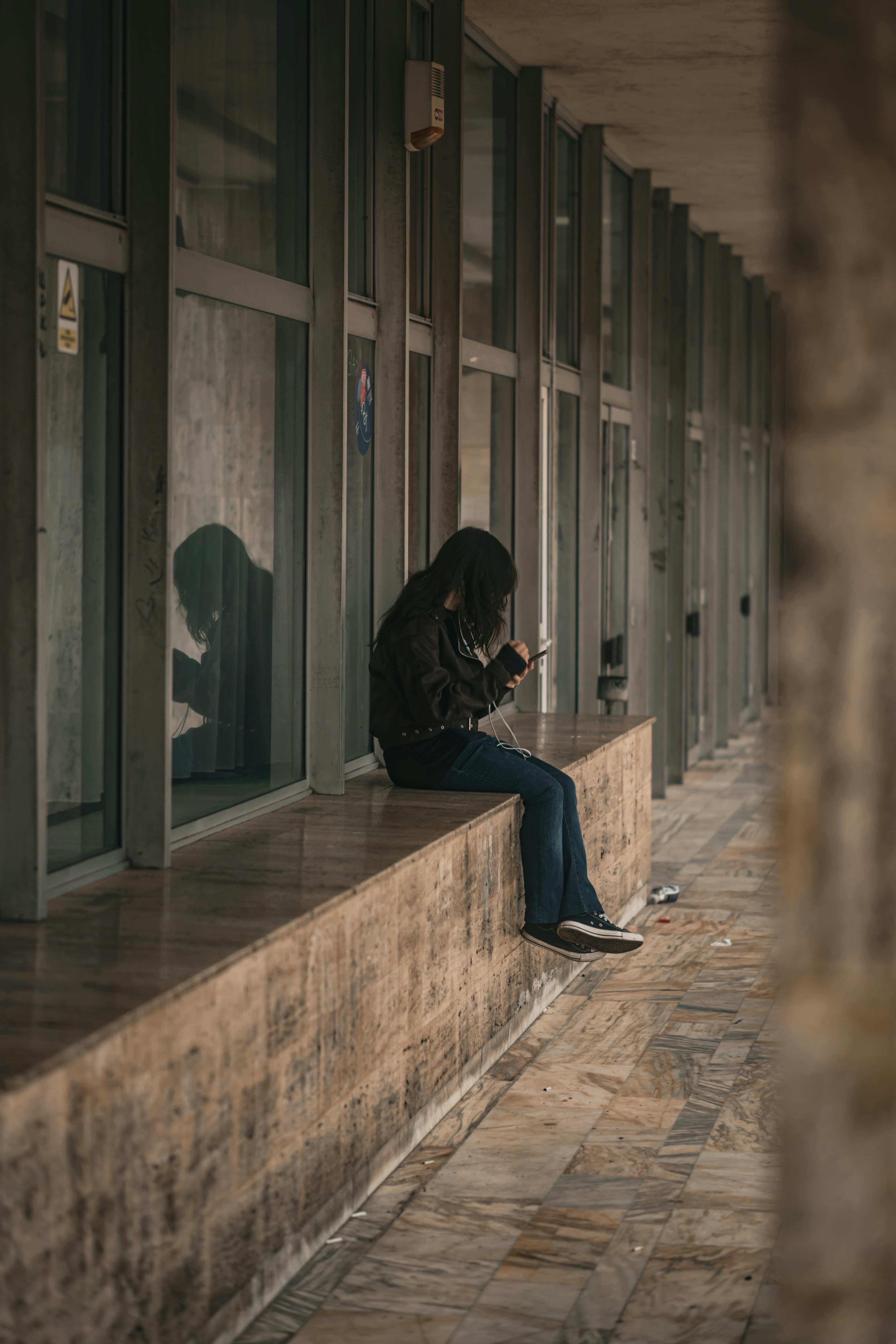 Young person sitting on ledge using phone