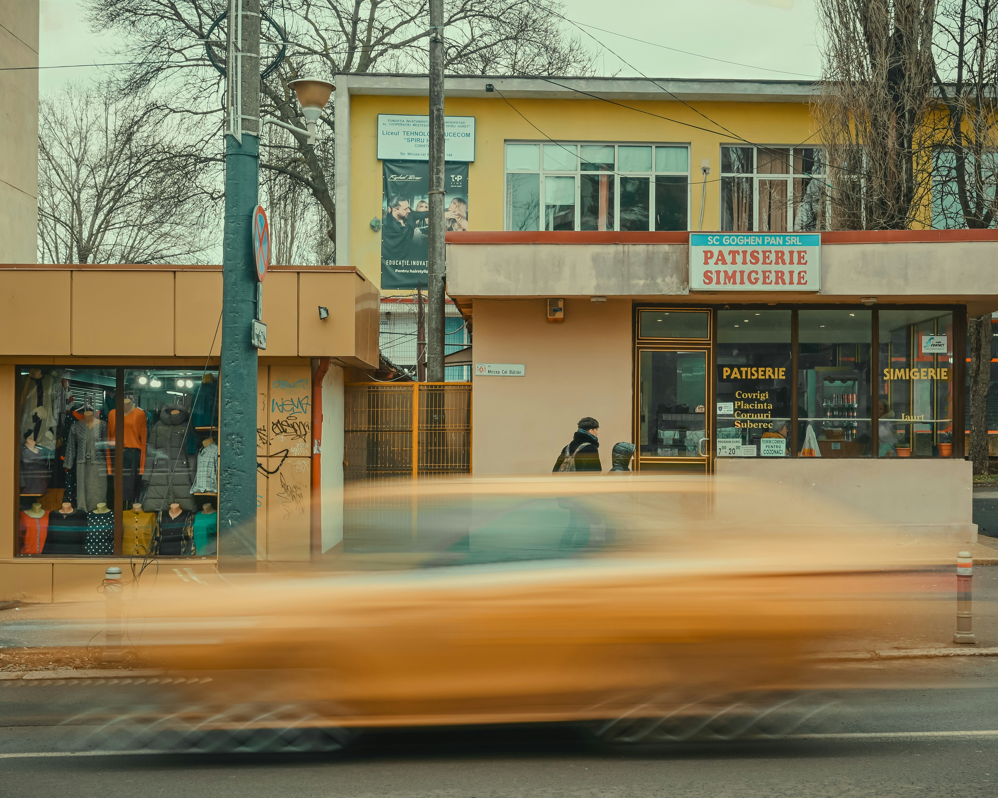 Yellow car blurred motion in front of storefronts