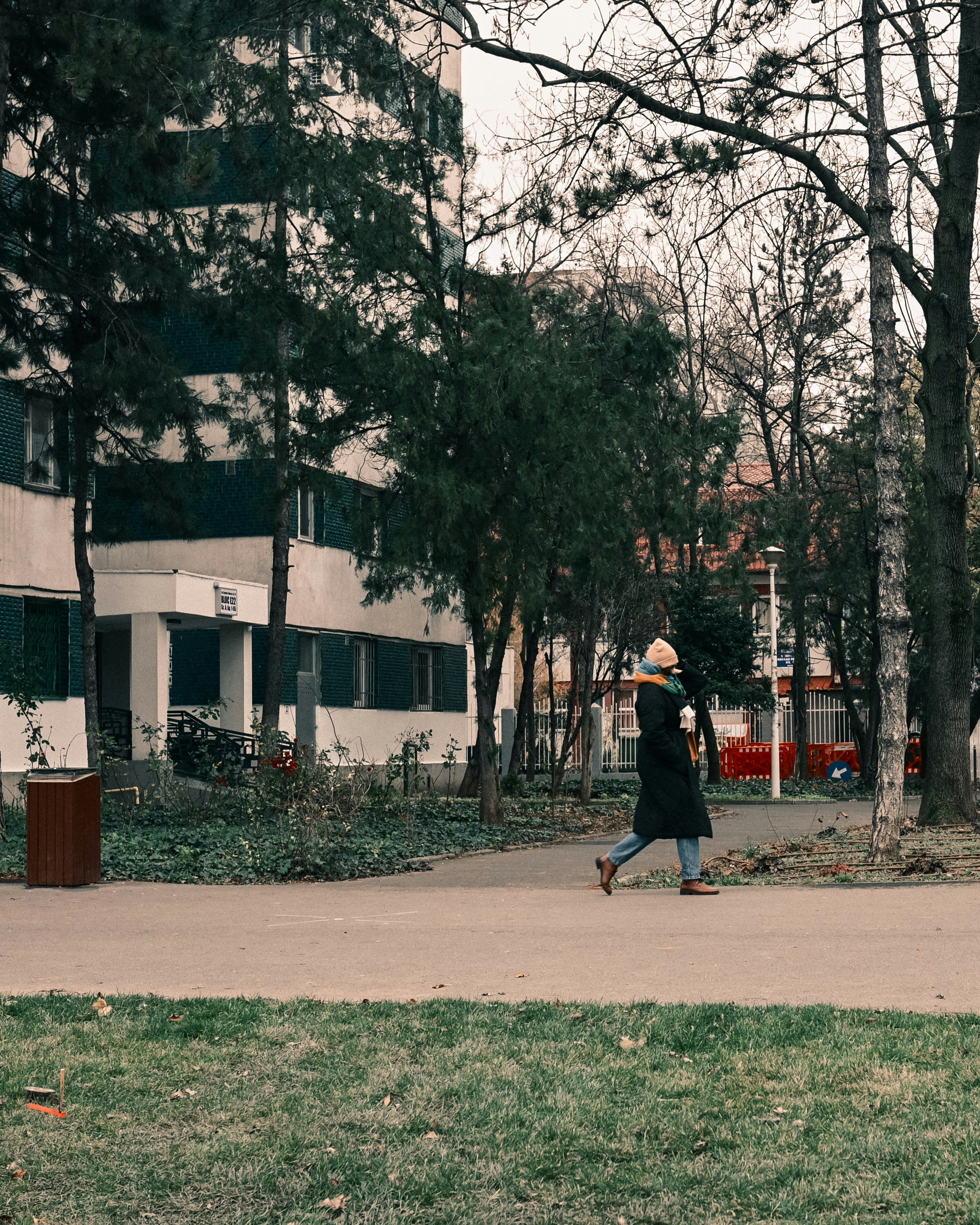 A person walks on a path near apartment buildings.