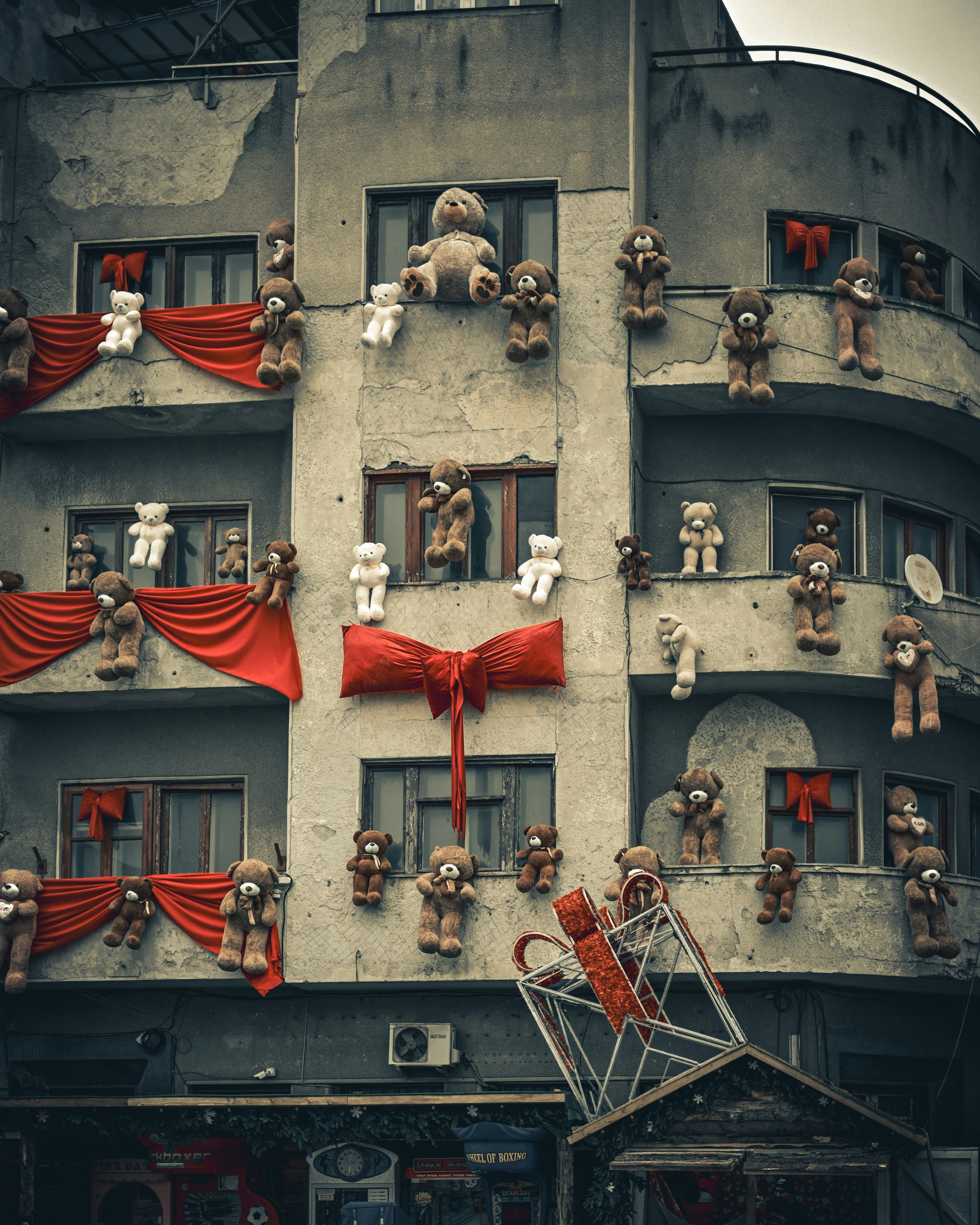 Building facade decorated with numerous teddy bears and red bows.