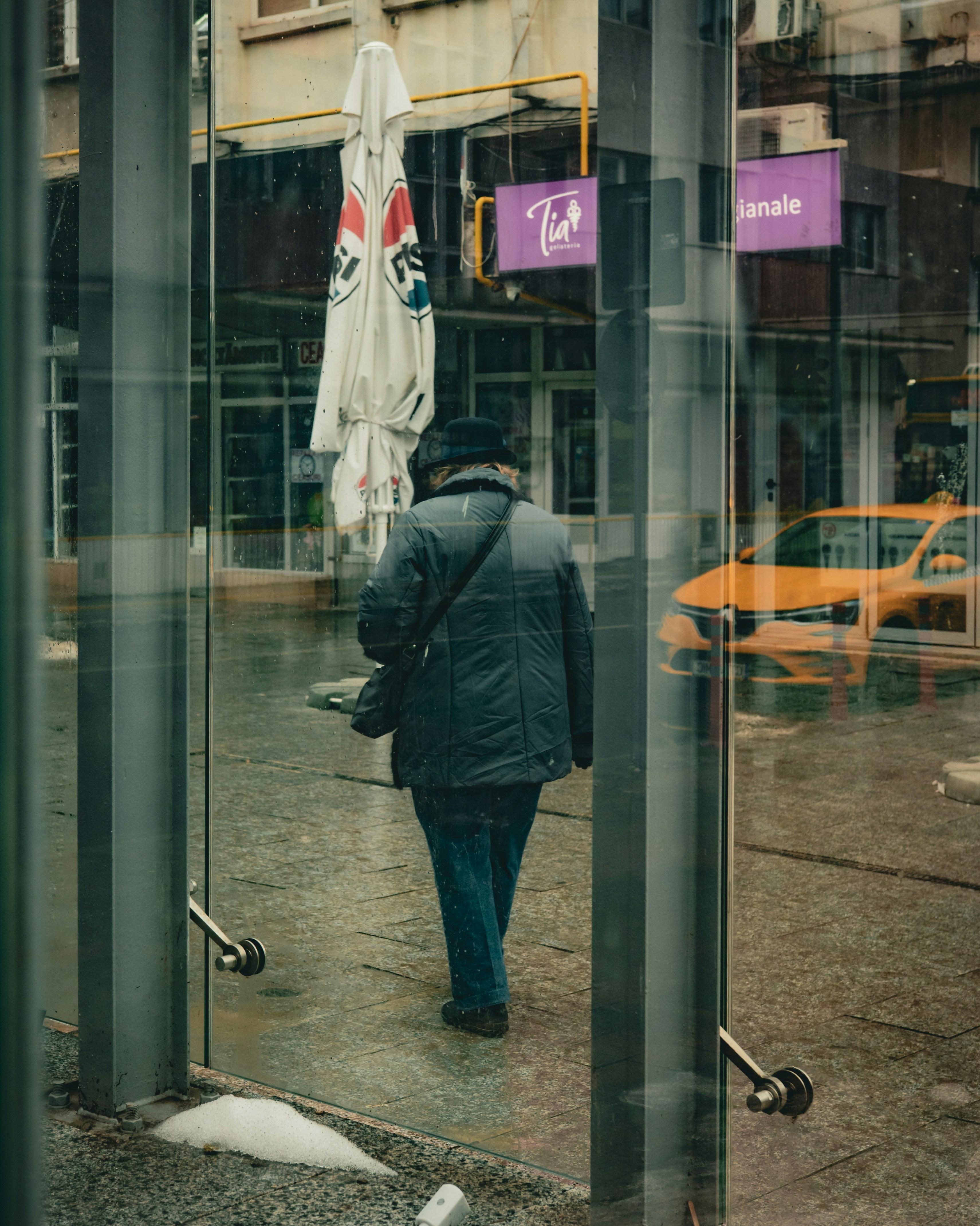 Person walks past a yellow taxi on street