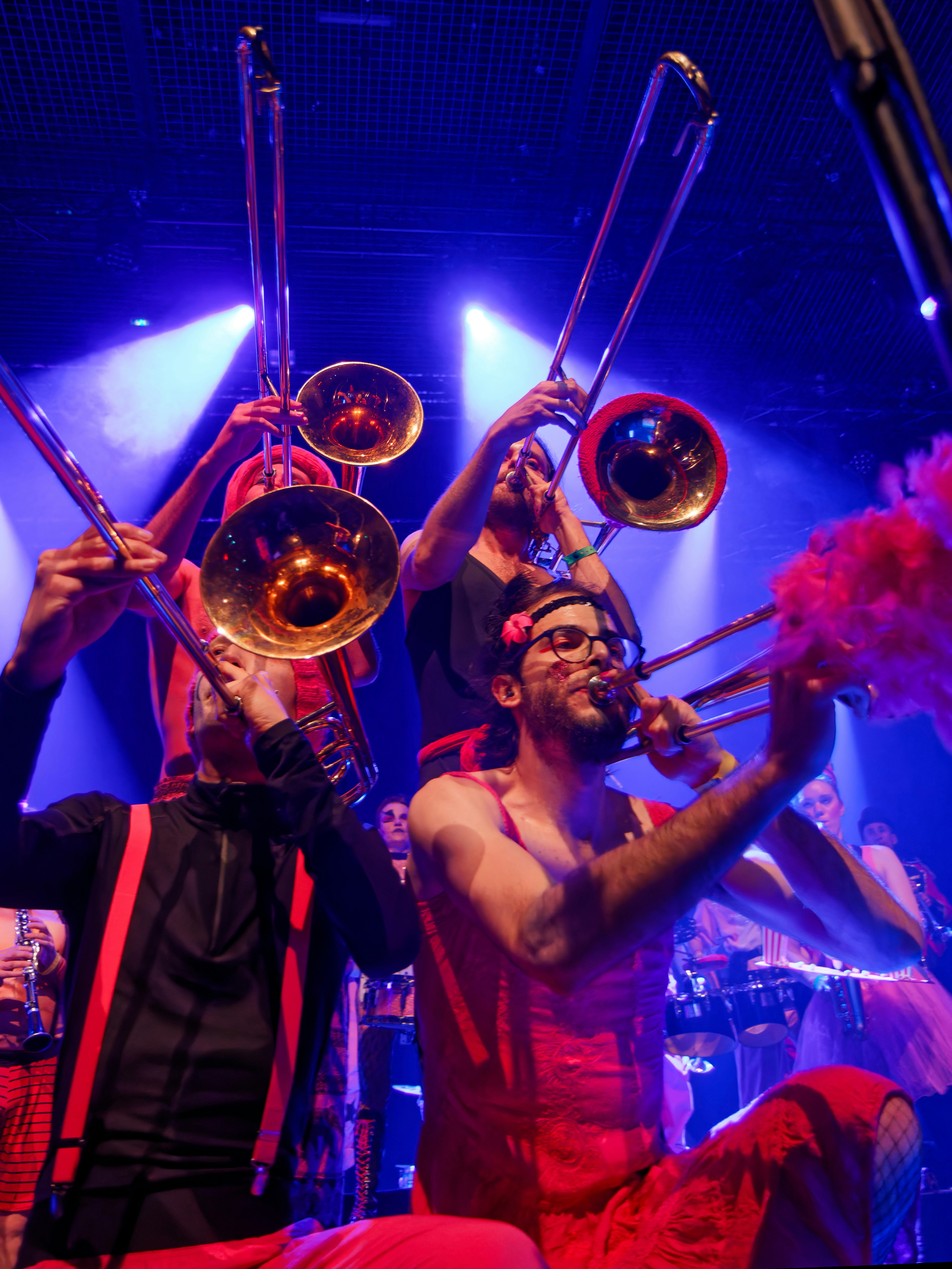 Músicos tocando trombones en un escenario muy iluminado.