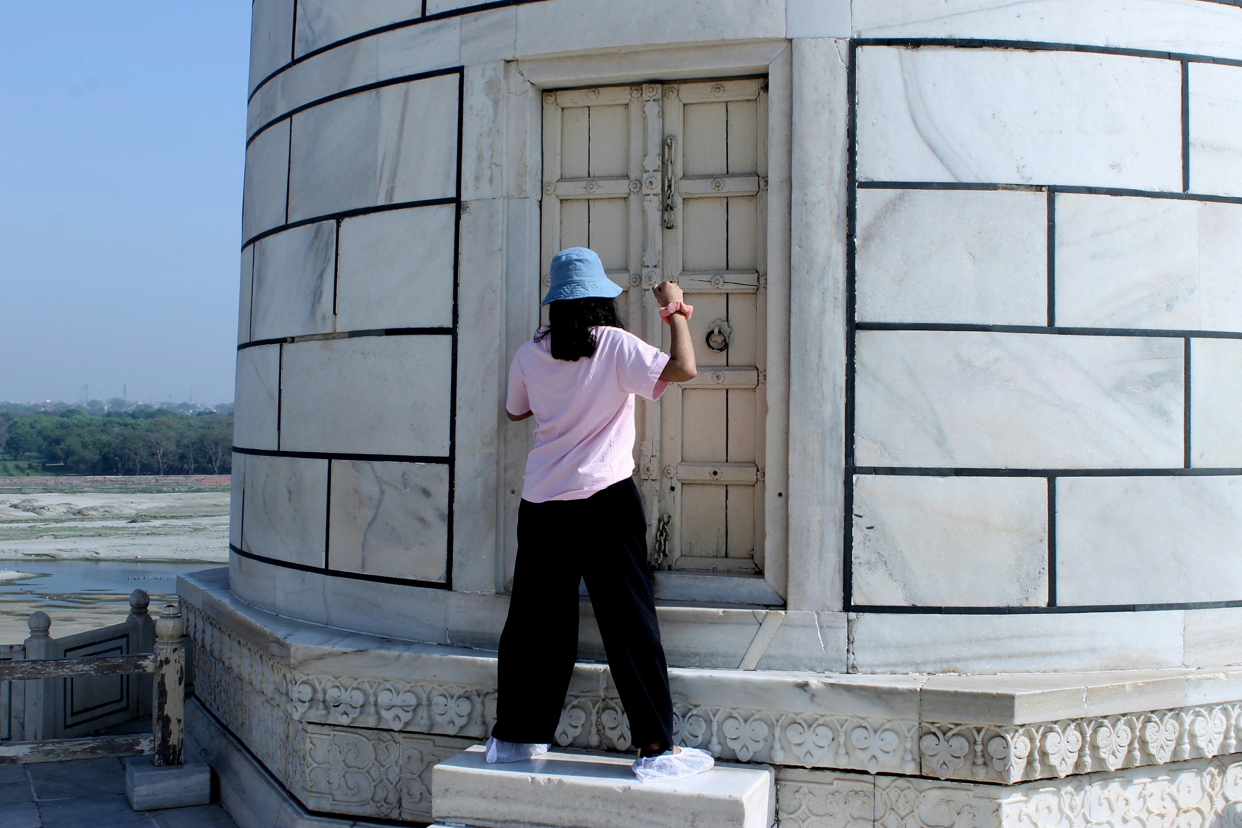 A person in a blue hat opens a white door.