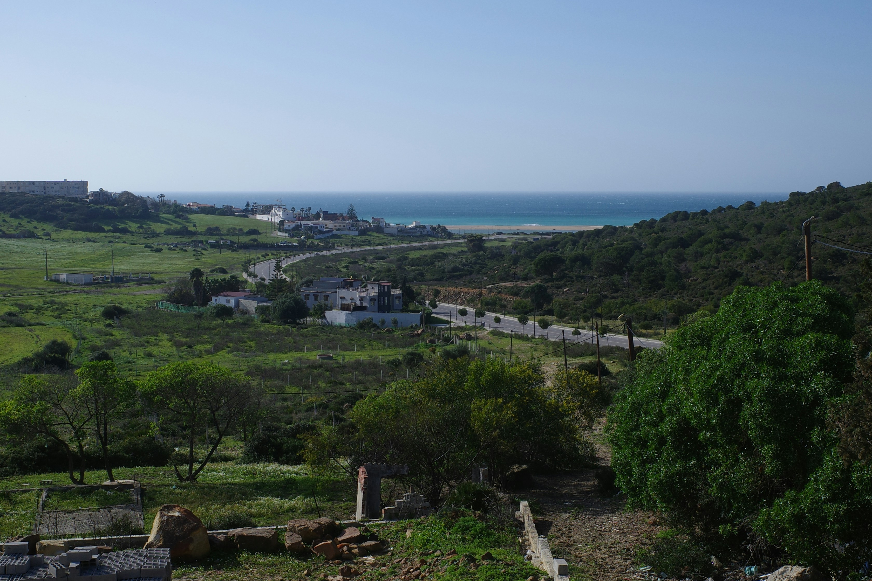 A scenic view of a coastal town with green hills.