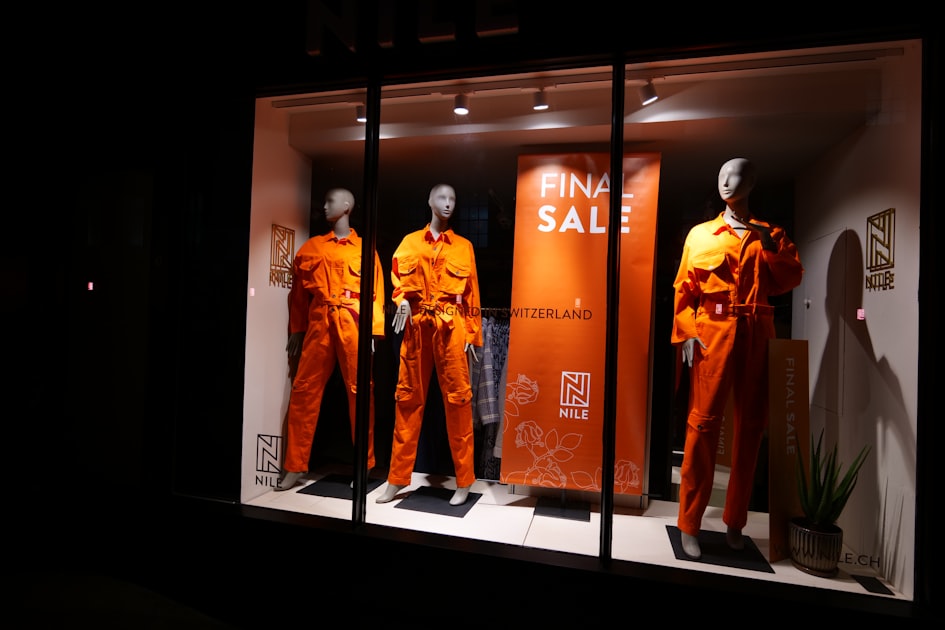 Mannequins in orange jumpsuits in a store window