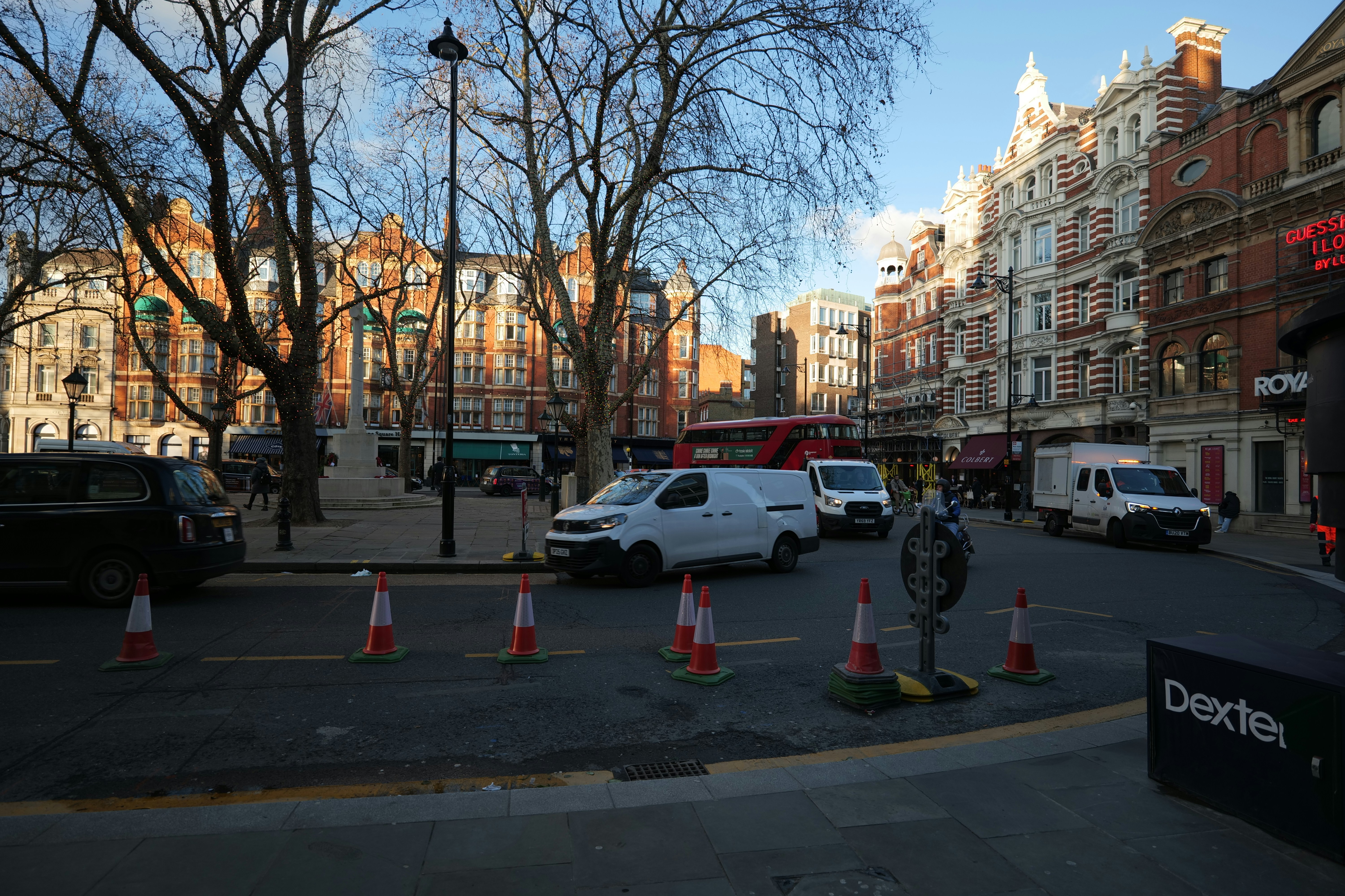 Street scene with buildings, vans, and traffic cones.
