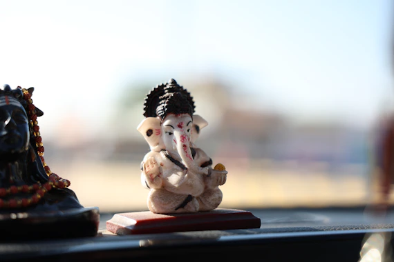 A small ganesha statue sits on a wooden base.