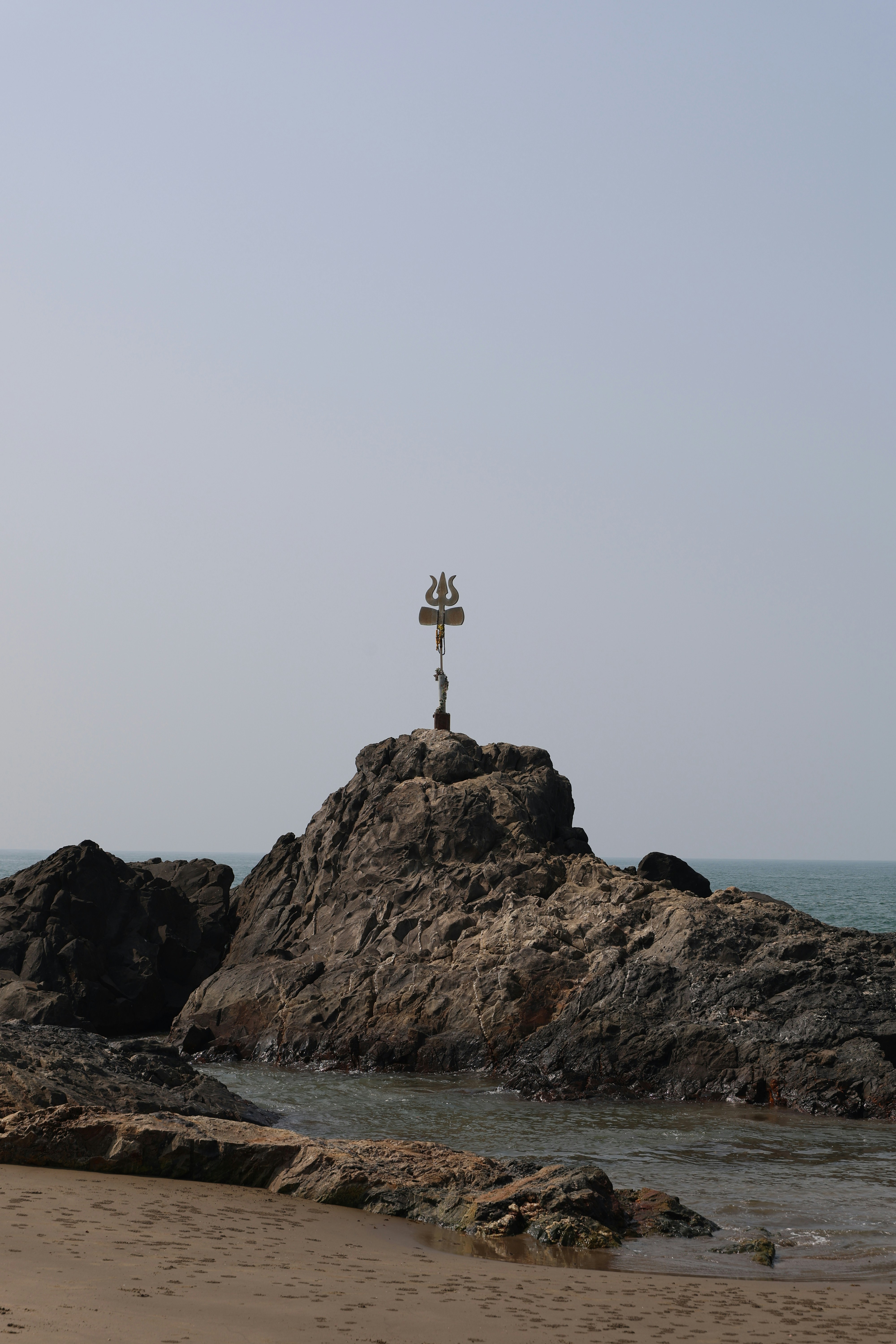 Trishul symbol atop a rock formation by the sea
