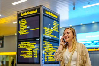 Woman talking on phone near south terminal departure board