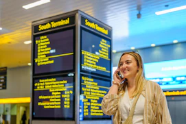 Woman talking on phone near south terminal departure board