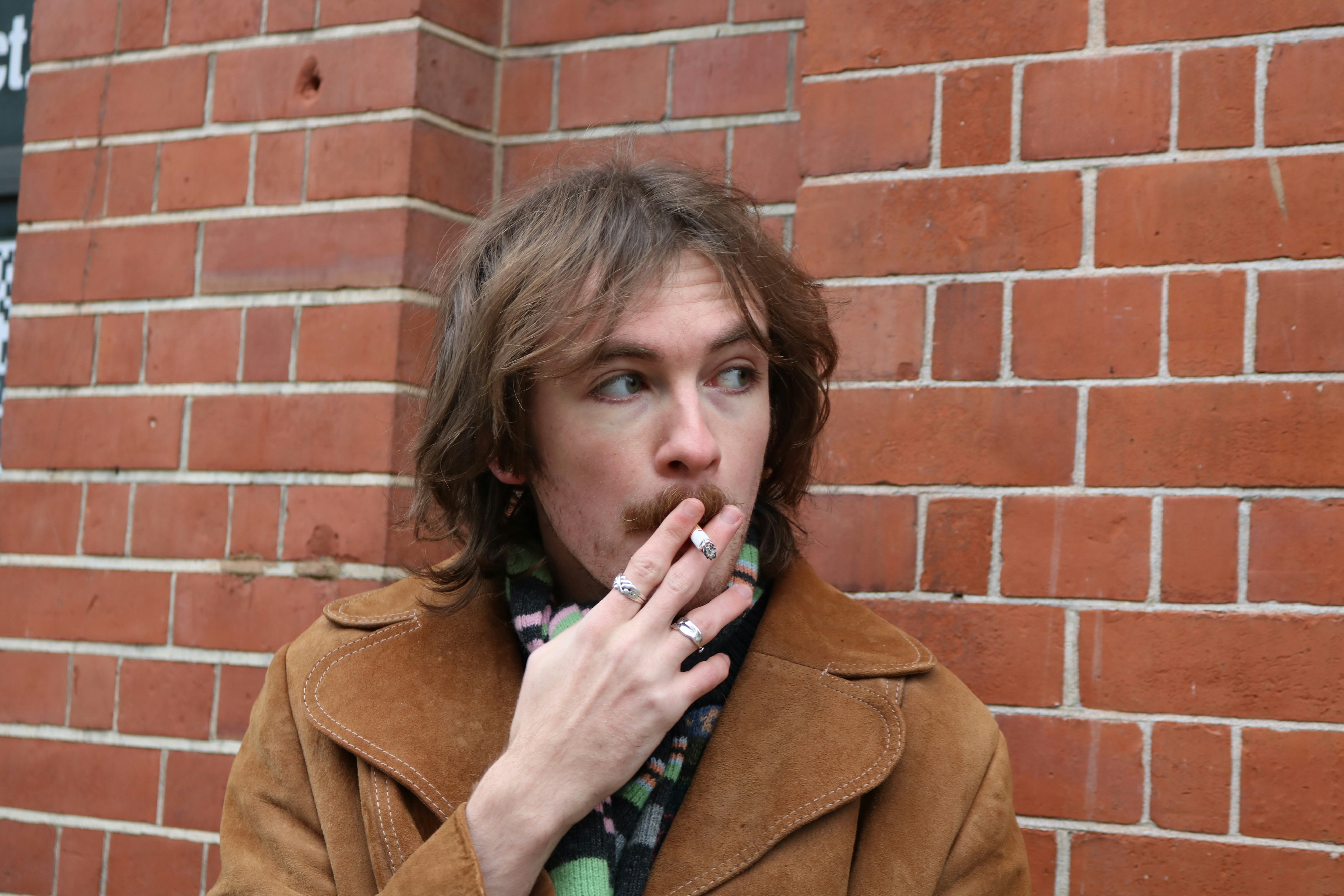 Man with cigarette in front of brick wall