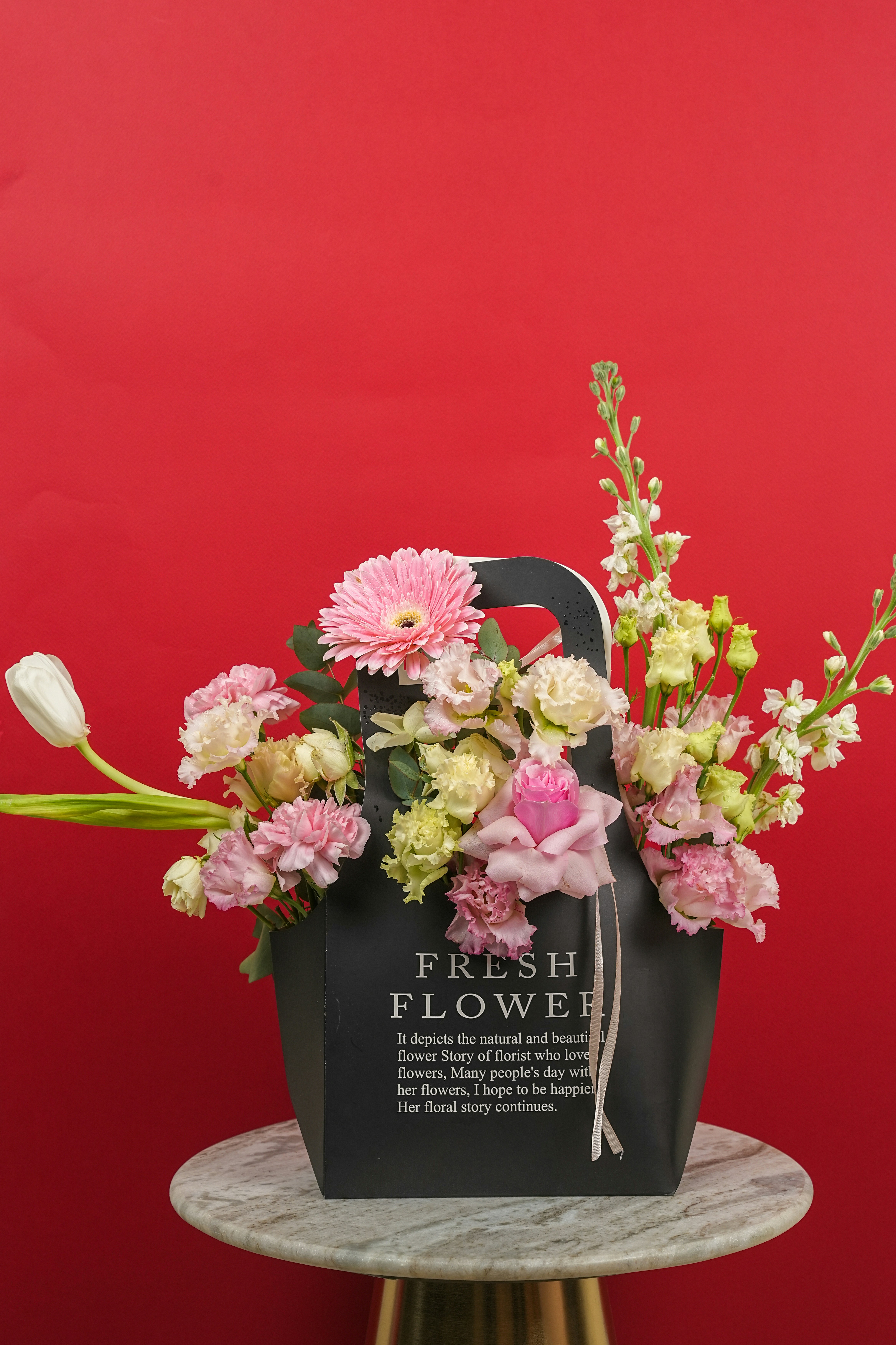 A black bag filled with assorted pink and white flowers.