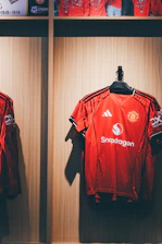 Red manchester united football jerseys hanging in a locker.