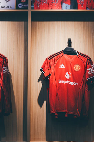 Red manchester united football jerseys hanging in a locker.